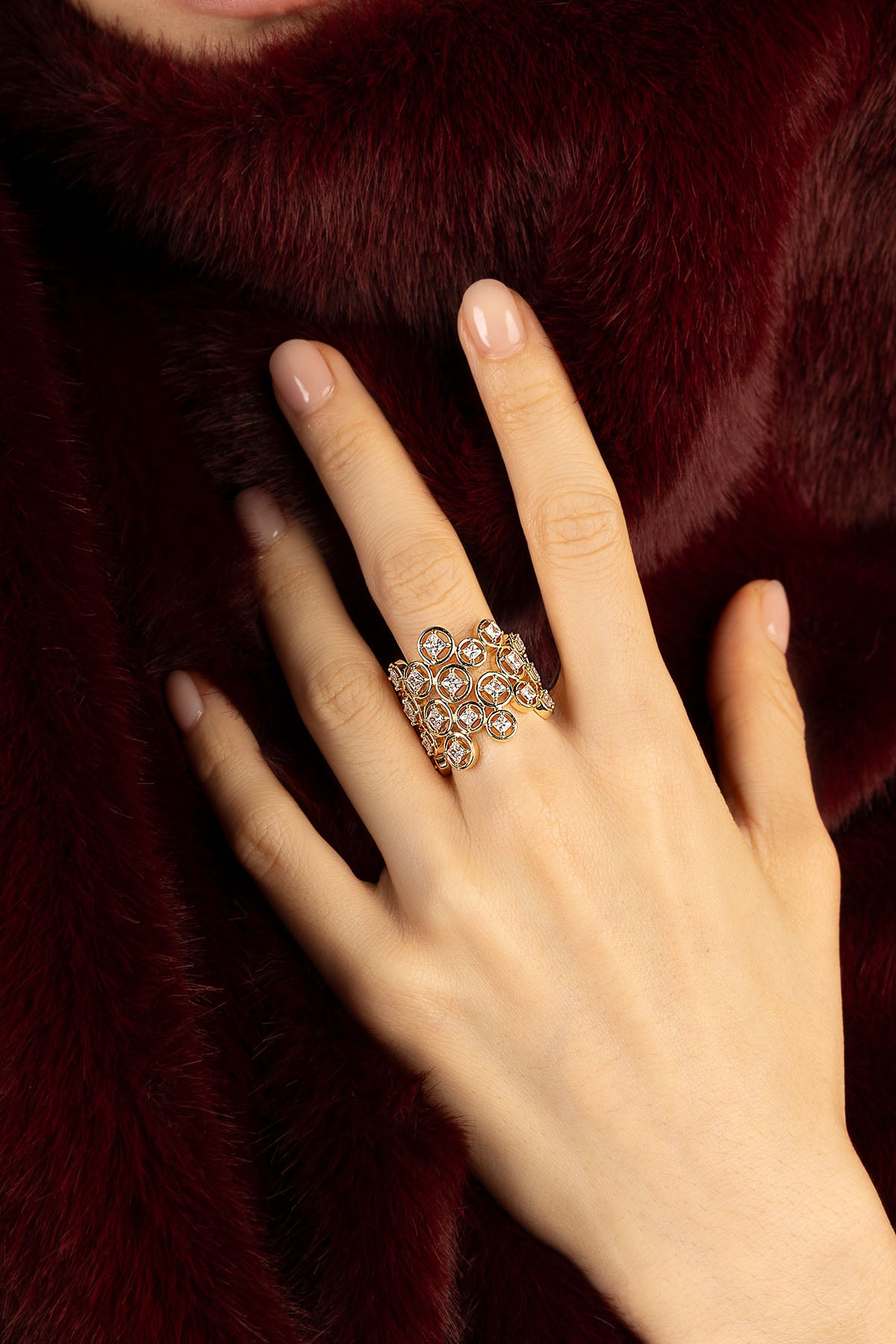 Woman wearing APM ring, a golden constellation glowing against deep burgundy softness.