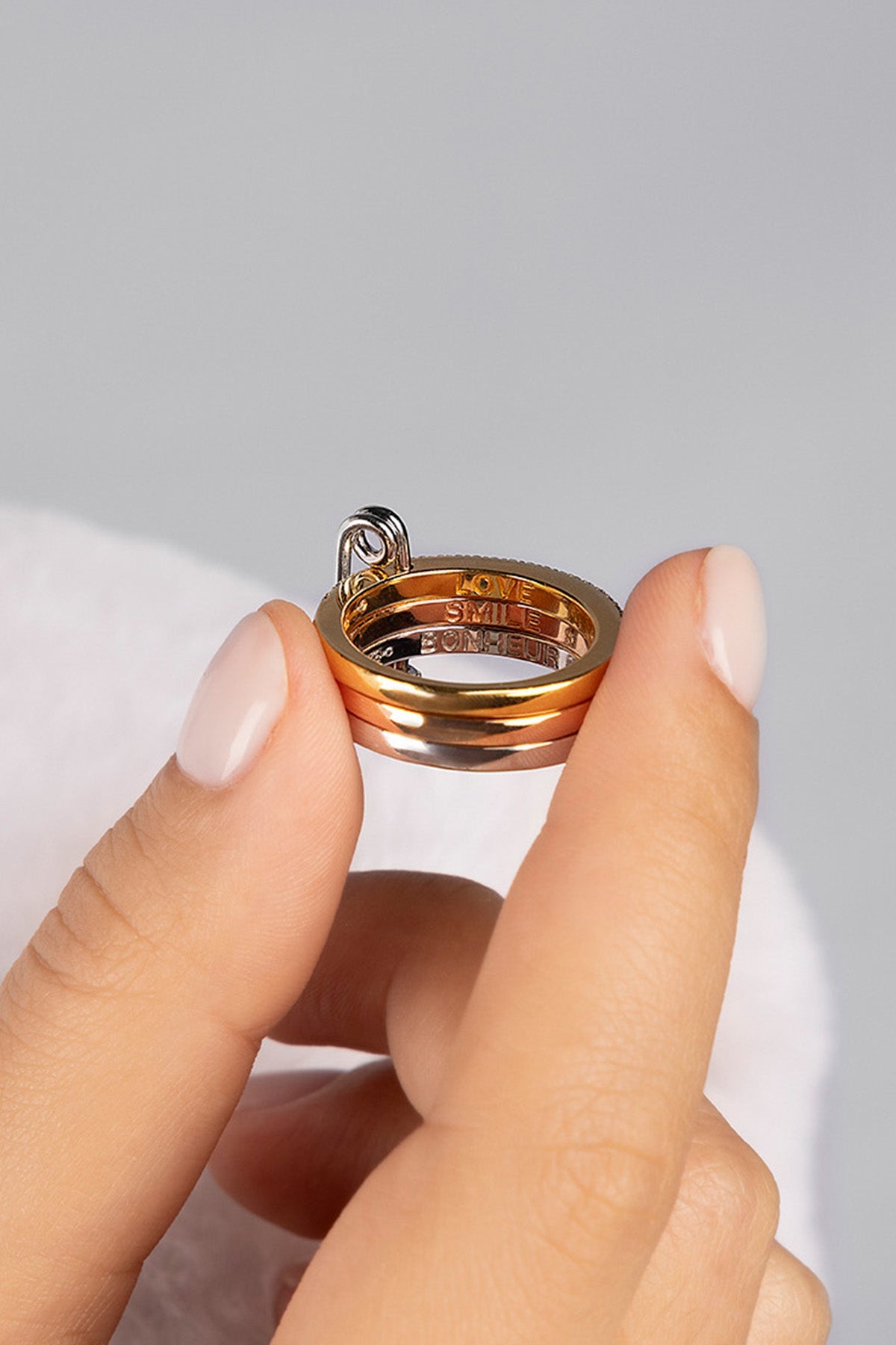 Hand holding a ring against a light gray background