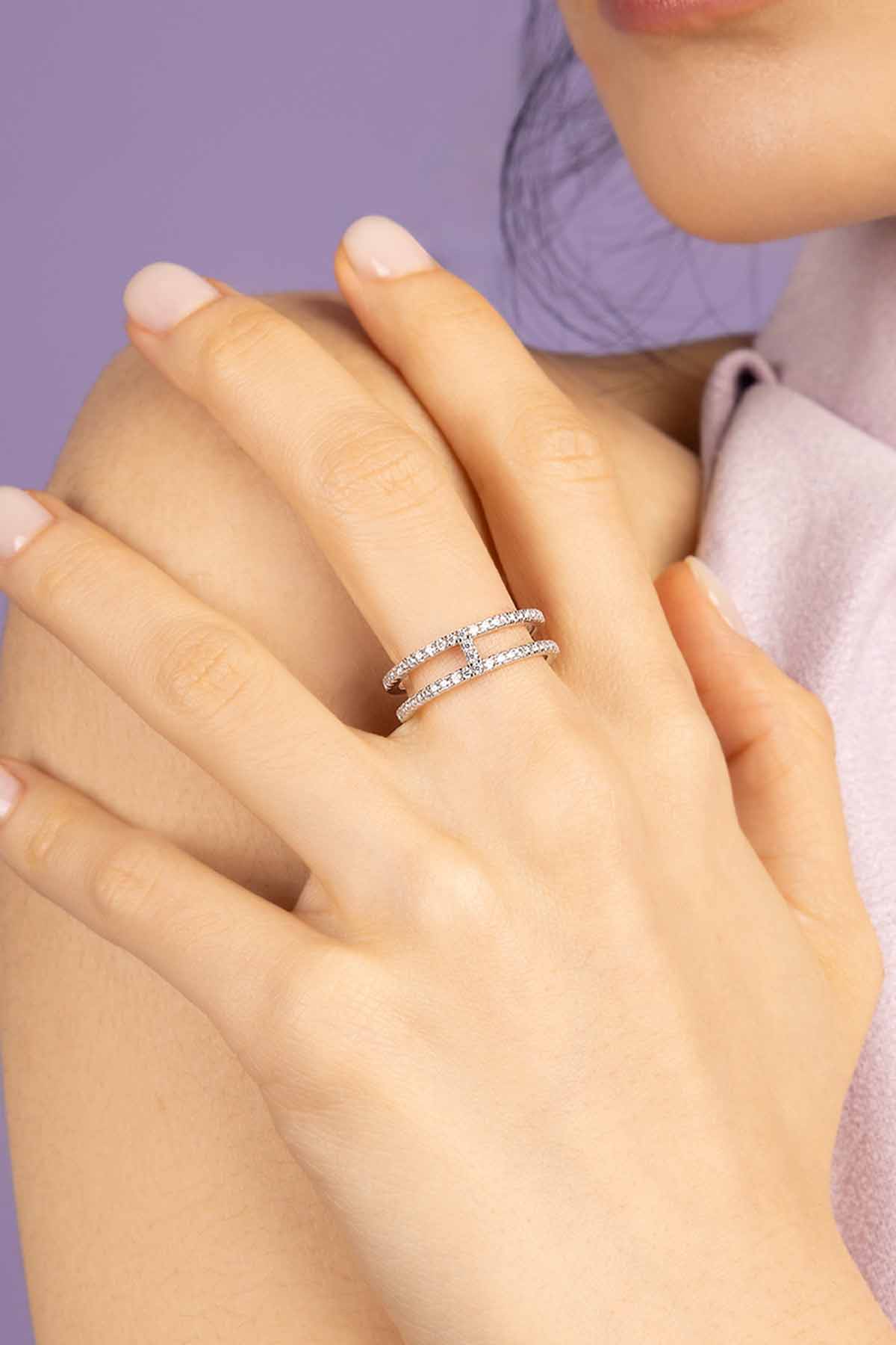Close-up of a hand wearing APM MONACO double line pave ring in silver on a purple background