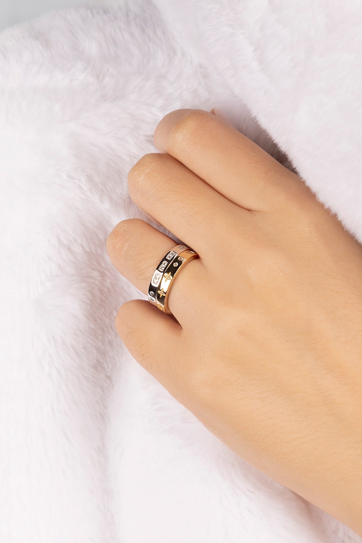 Hand wearing a gold ring on a white background