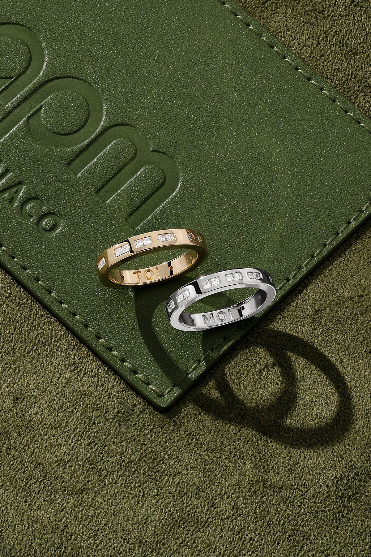 Two rings on a green surface with 'apm monaco' branding.