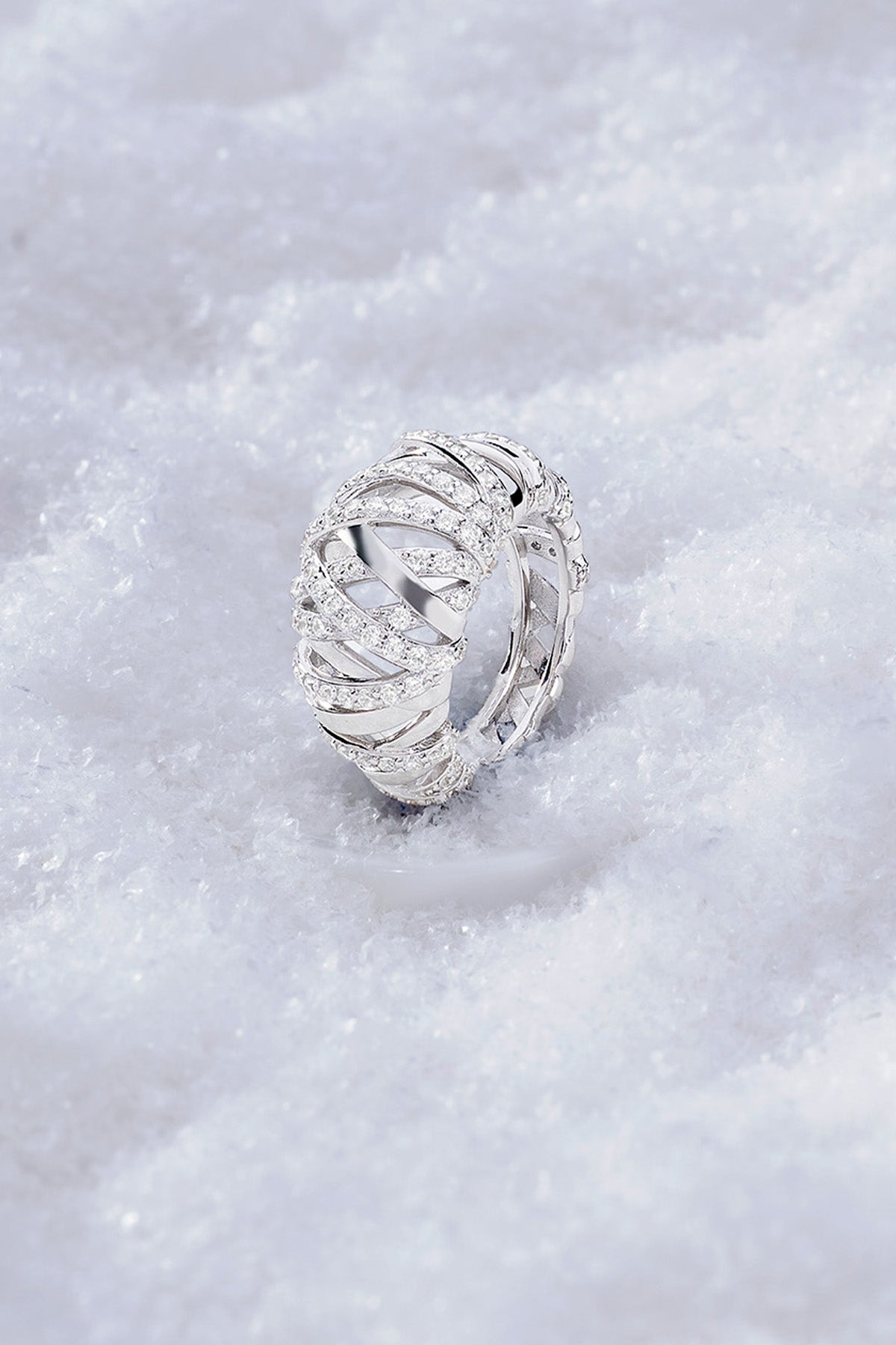 APM MONACO enlace ring in silver with intricate design on a snowy background