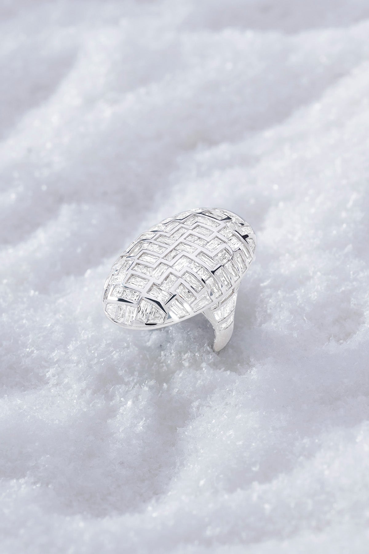 APM MONACO statement labyrinth ring in silver with a textured design on a white snowy background