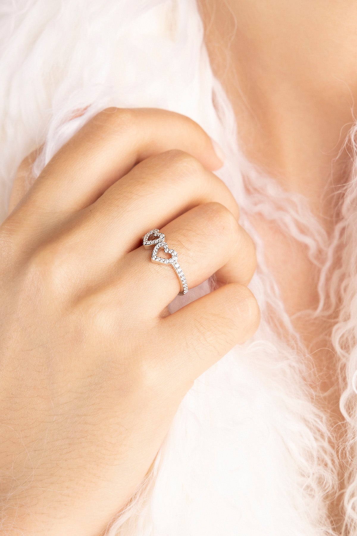 APM MONACO silver heart-shaped ring on a model's finger with a soft white background