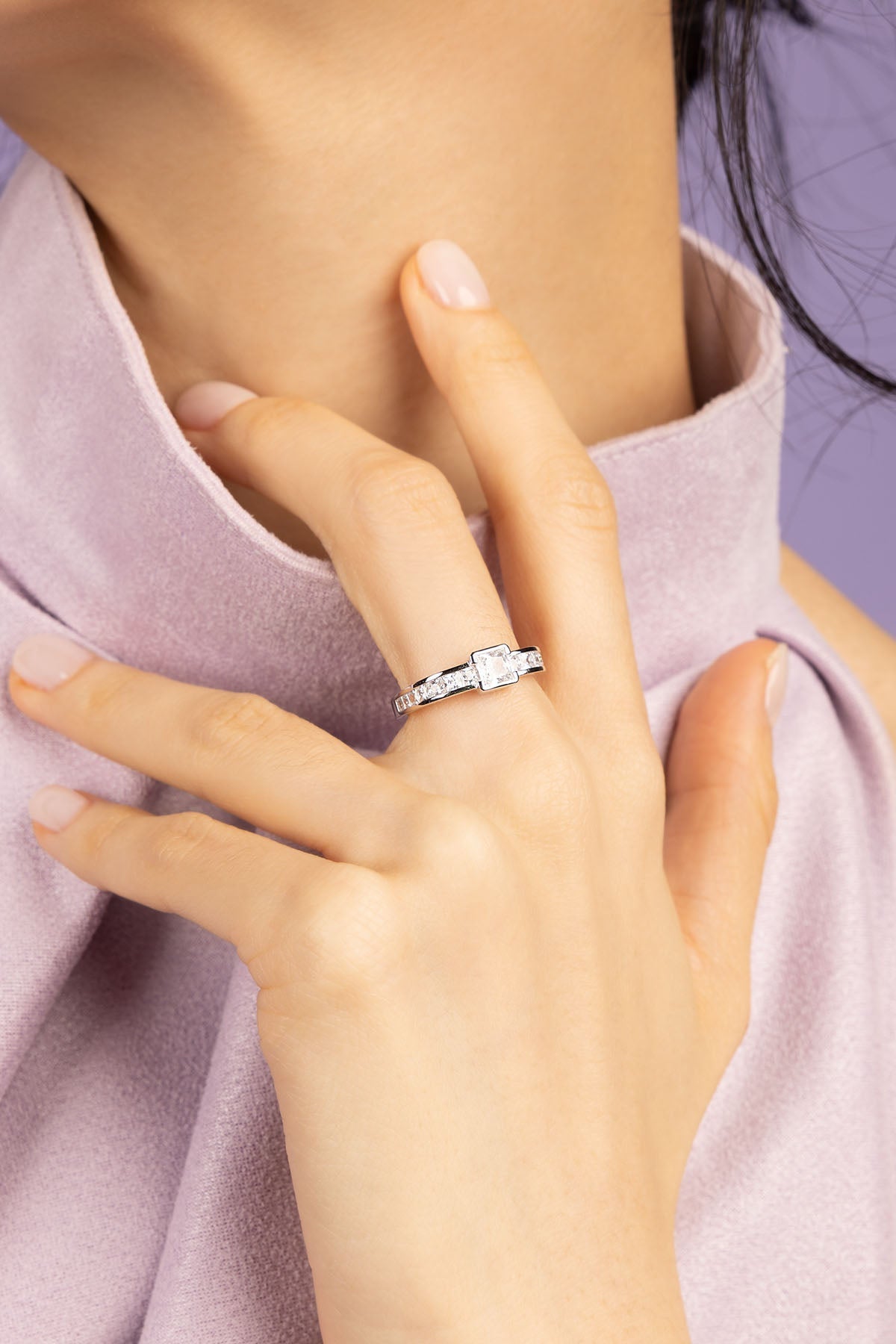 Hand wearing a white zirconia ring with a purple shirt