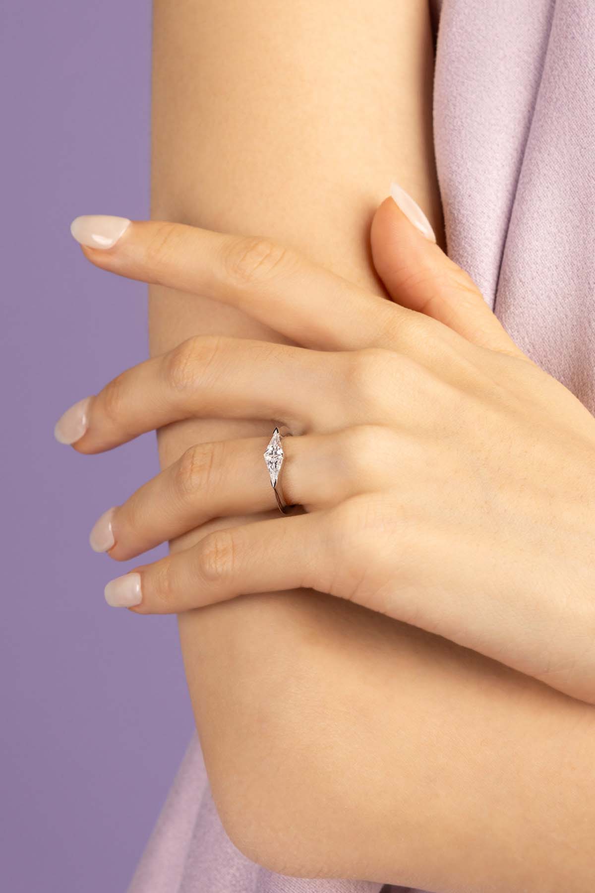 Close-up of a hand wearing a zirconia ring against a purple background