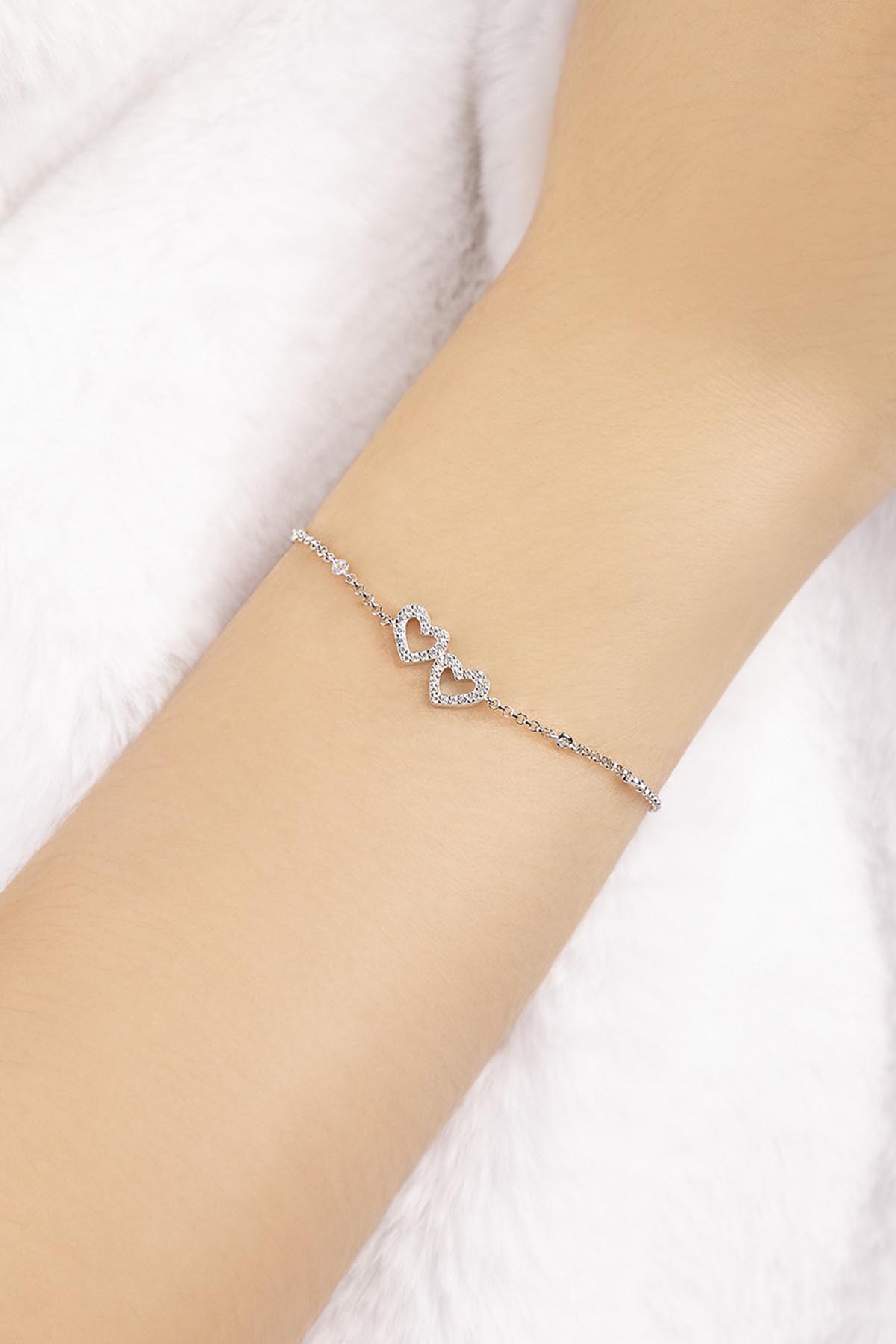 APM MOANCO silver bracelet with heart-shaped design on a model's wrist against a white background