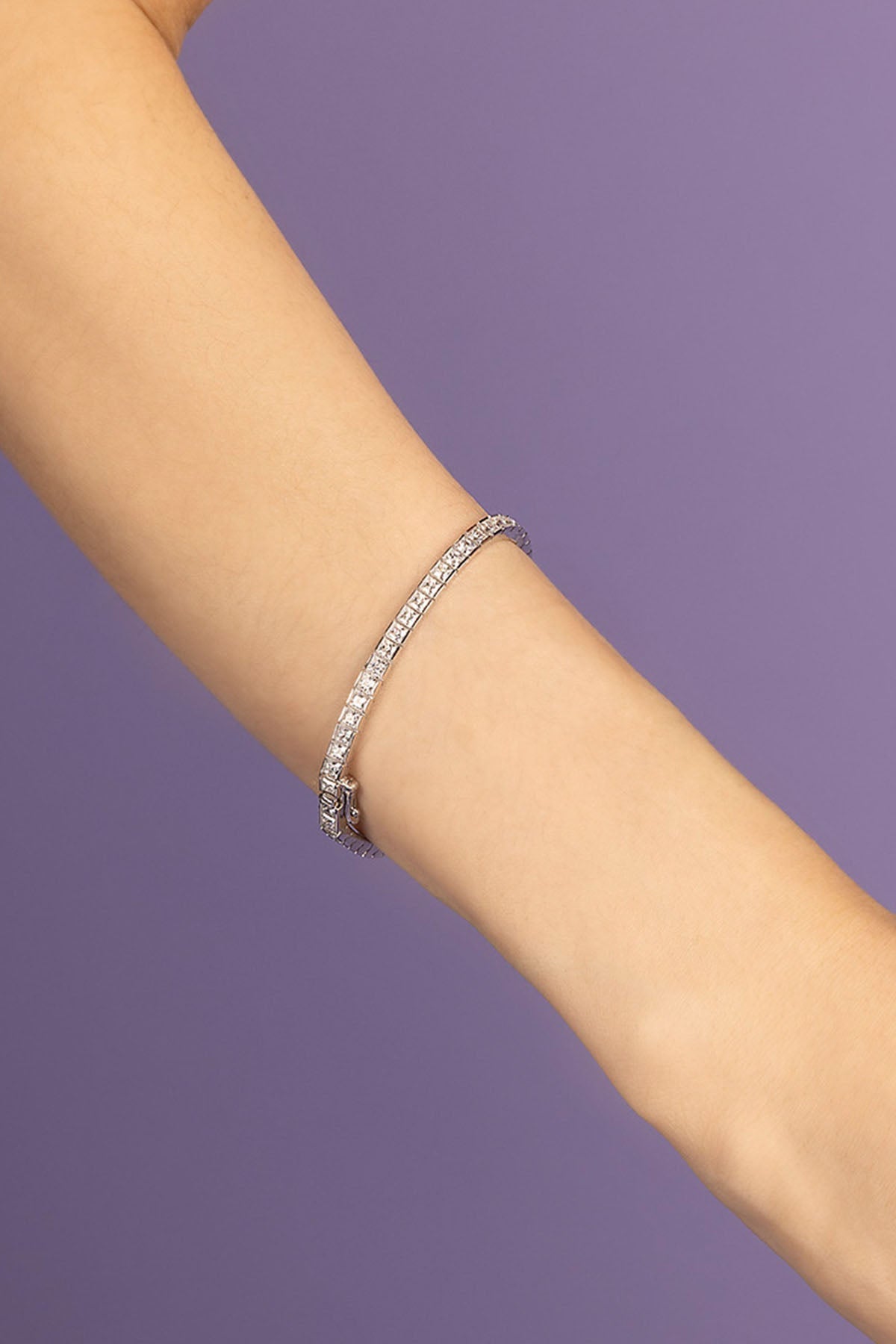Silver bracelet on a person's wrist against a purple background