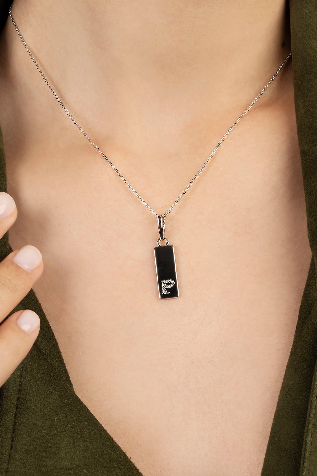 Necklace with a pendant featuring the letter 'P' on a person's neck.