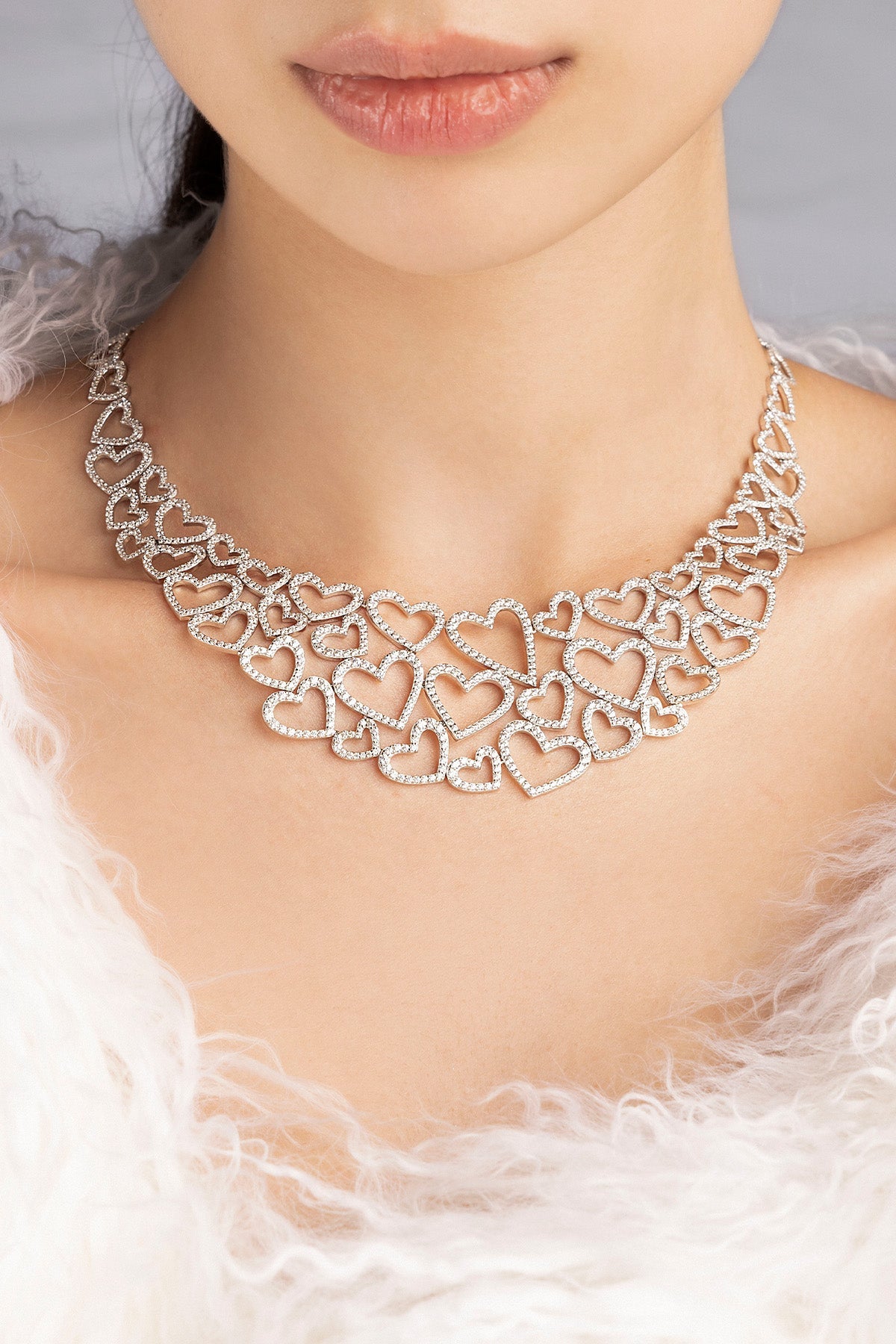 Silver heart-shaped necklace from APM MONACO worn by a model with a soft focus background