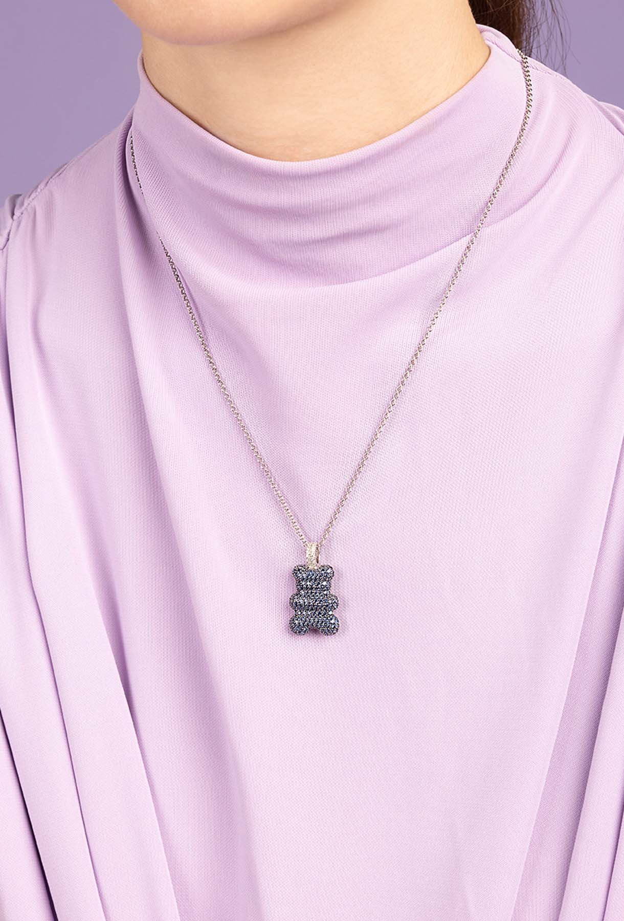 Person wearing a lavender top with a necklace featuring a bear-shaped pendant.