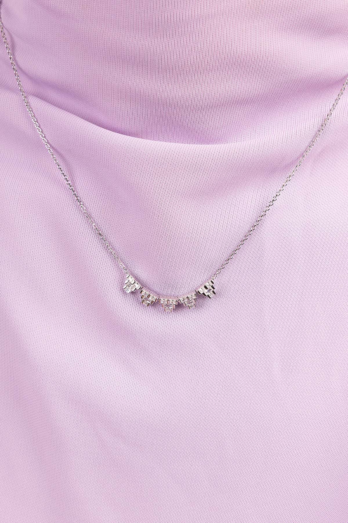 Silver necklace with small zirconia stones on a light purple fabric background