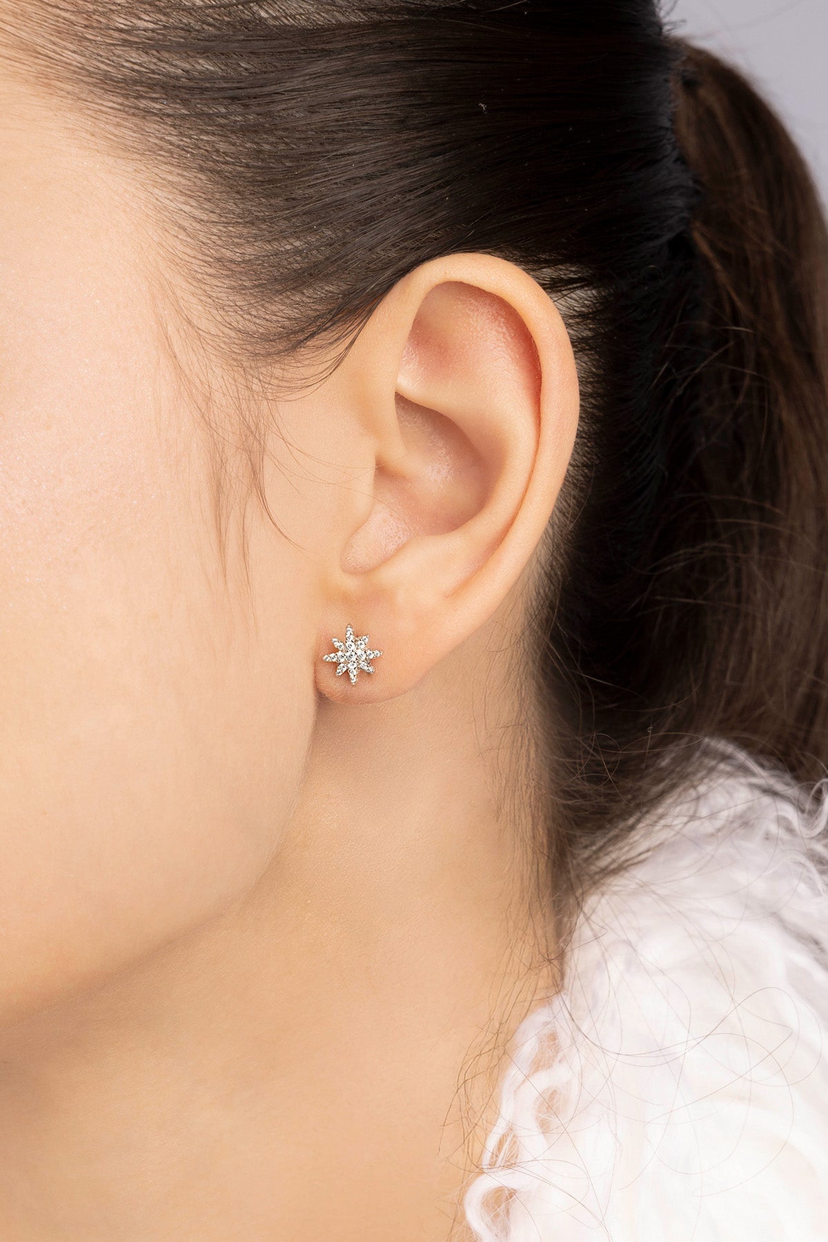 Close-up of an ear wearing a stud earring with a blurred background