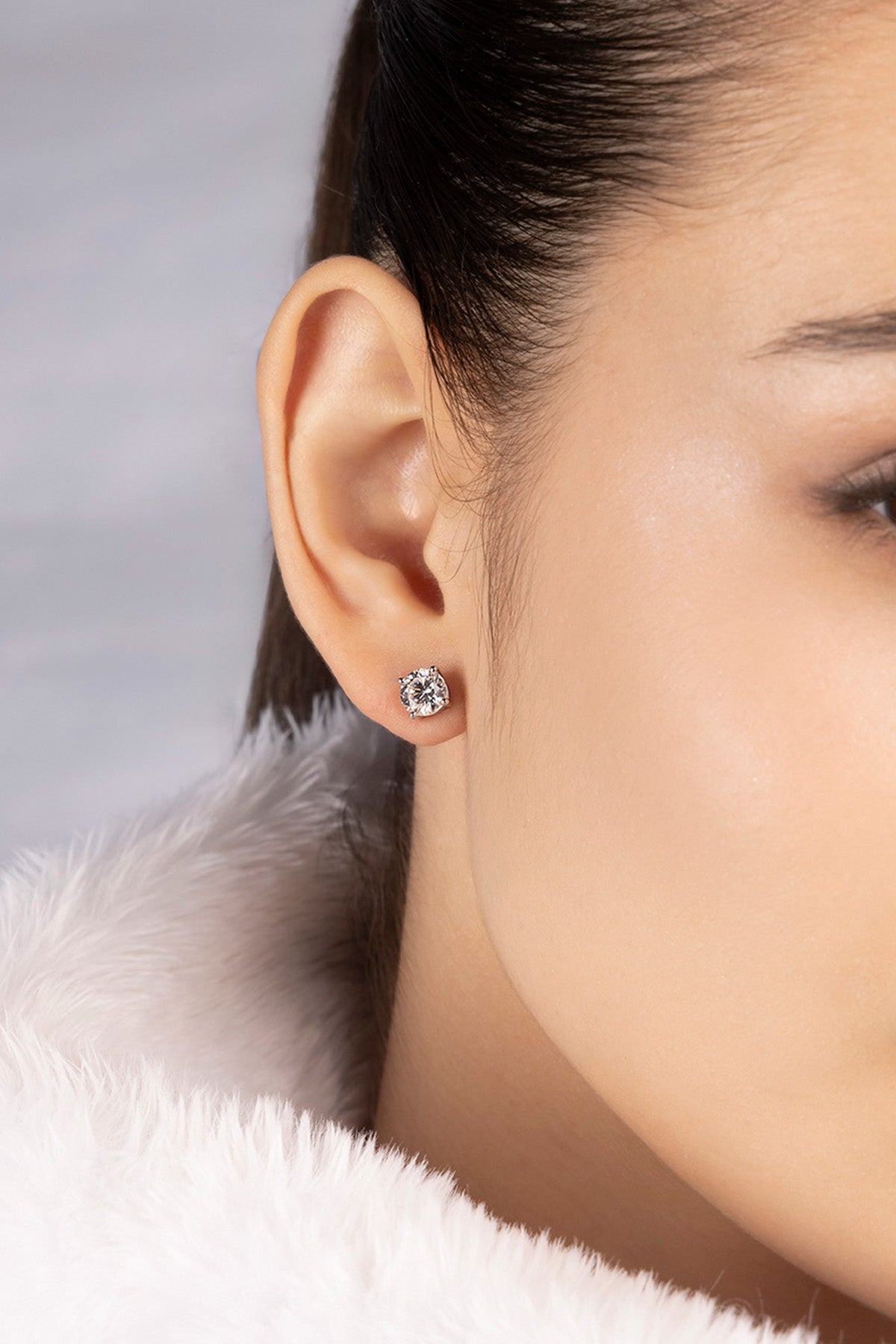 Close-up of a person wearing a round stud earring in silver from APM MONACO