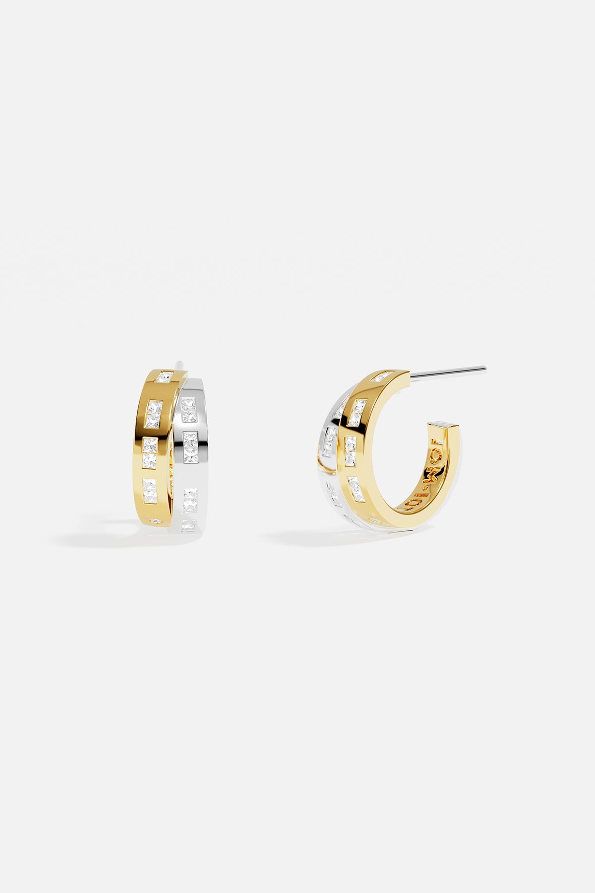 Earrings APM Monaco. Two-tone white and yellow gold intertwined hoop earrings with pavé cubic zirconia accents and morse-code detailing.