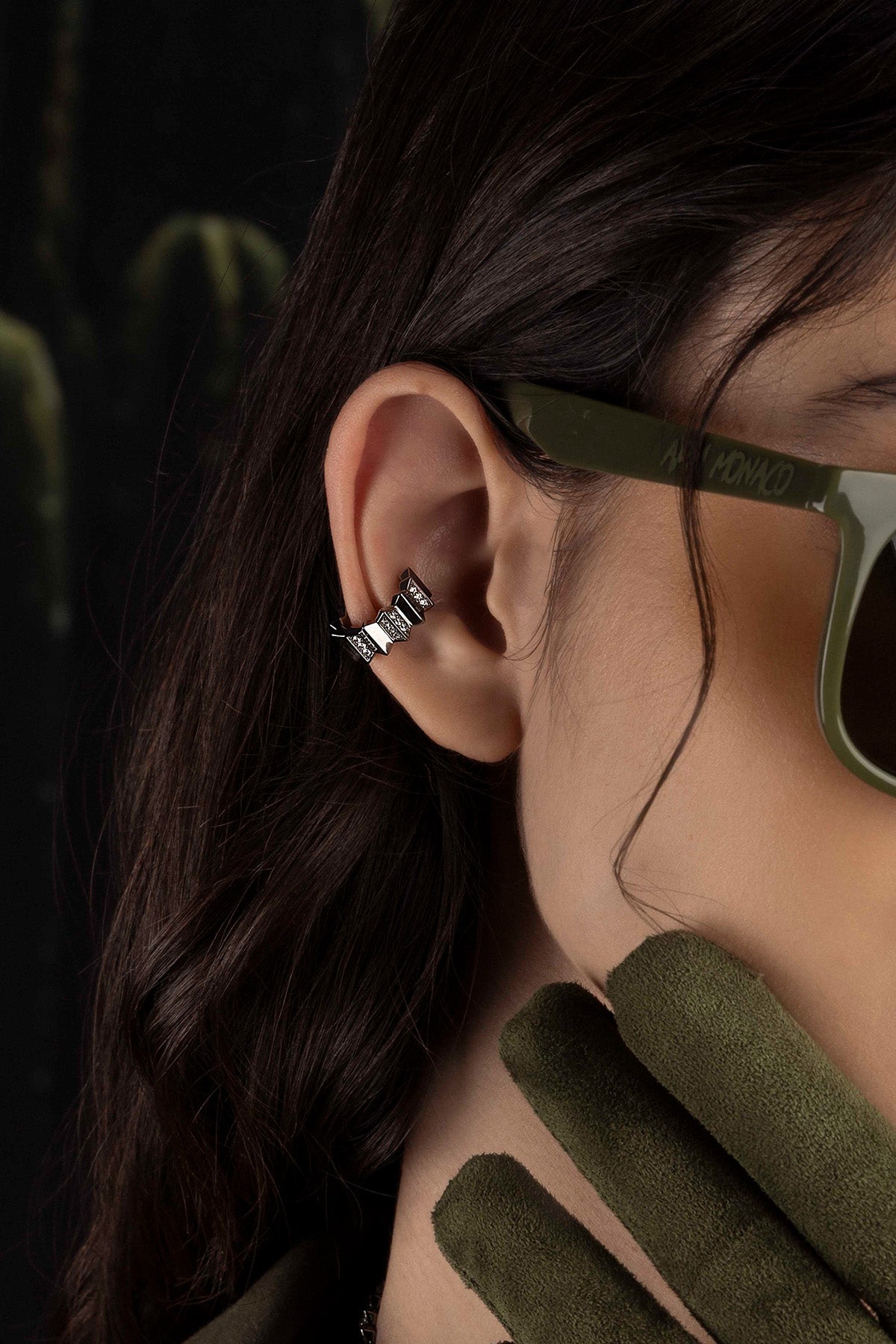 Close-up of a model wearing an ear cuff against a dark background