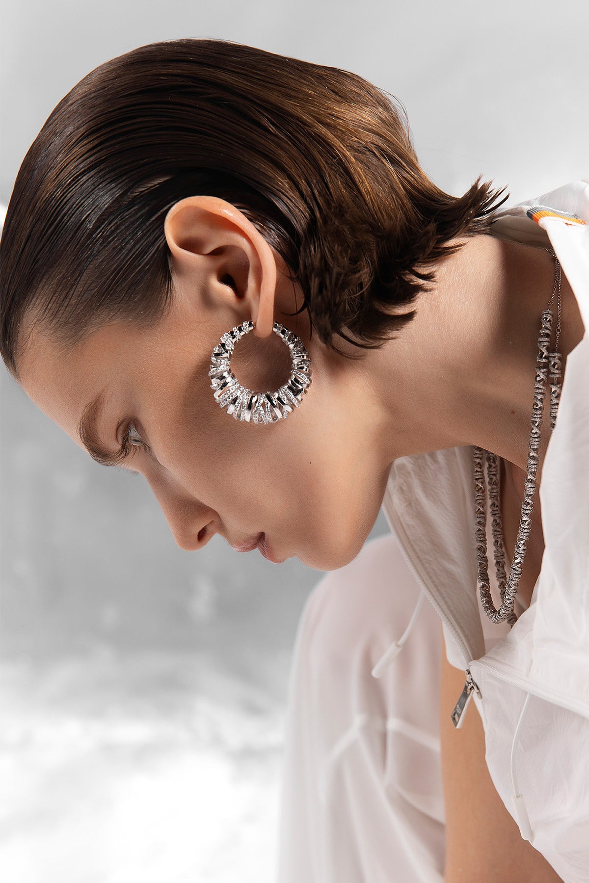 Woman wearing enlace hoop earrings from APM MONACO with a blurred background