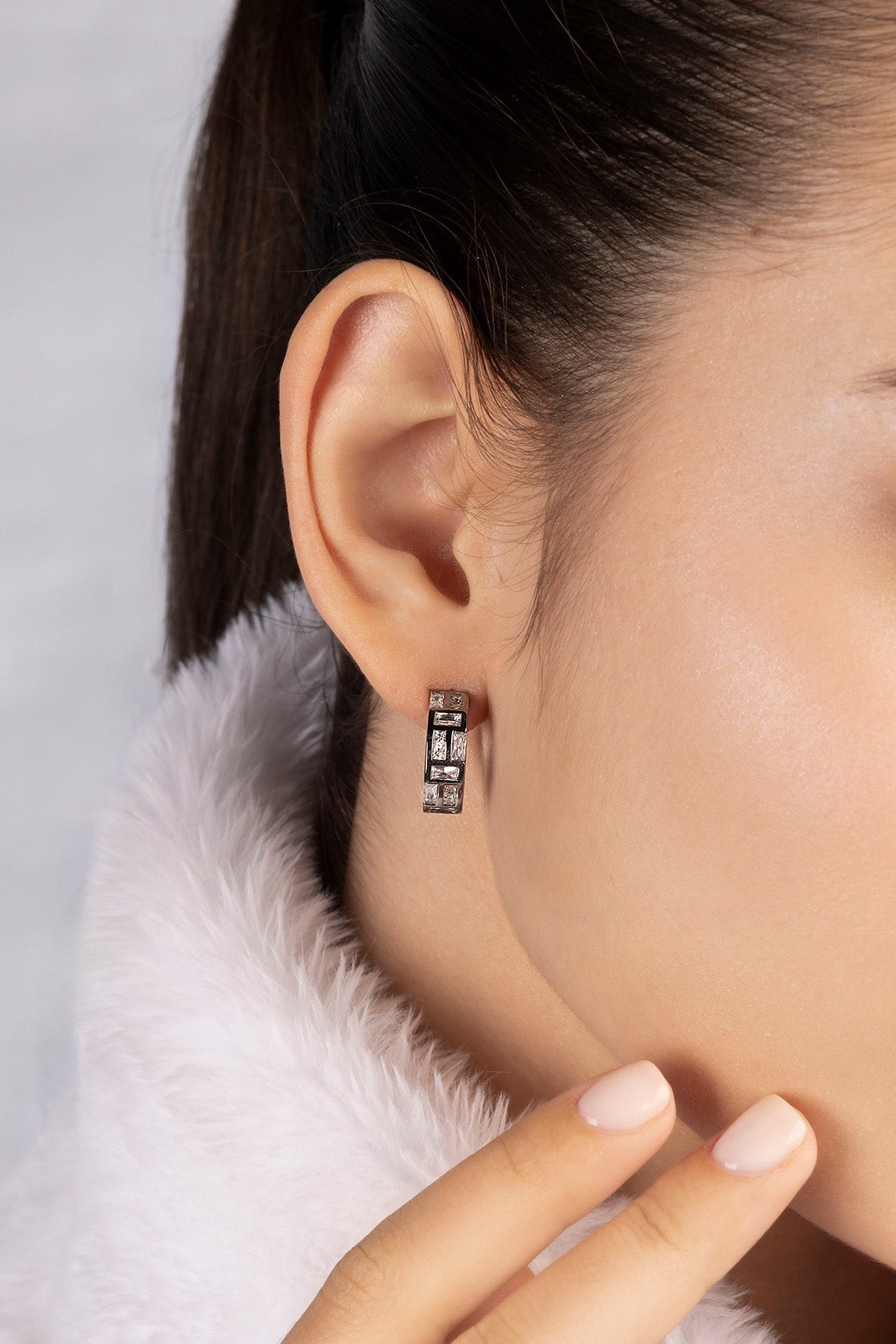 Pair of APM MONACO silver hoop earrings with clear white stones worn on model