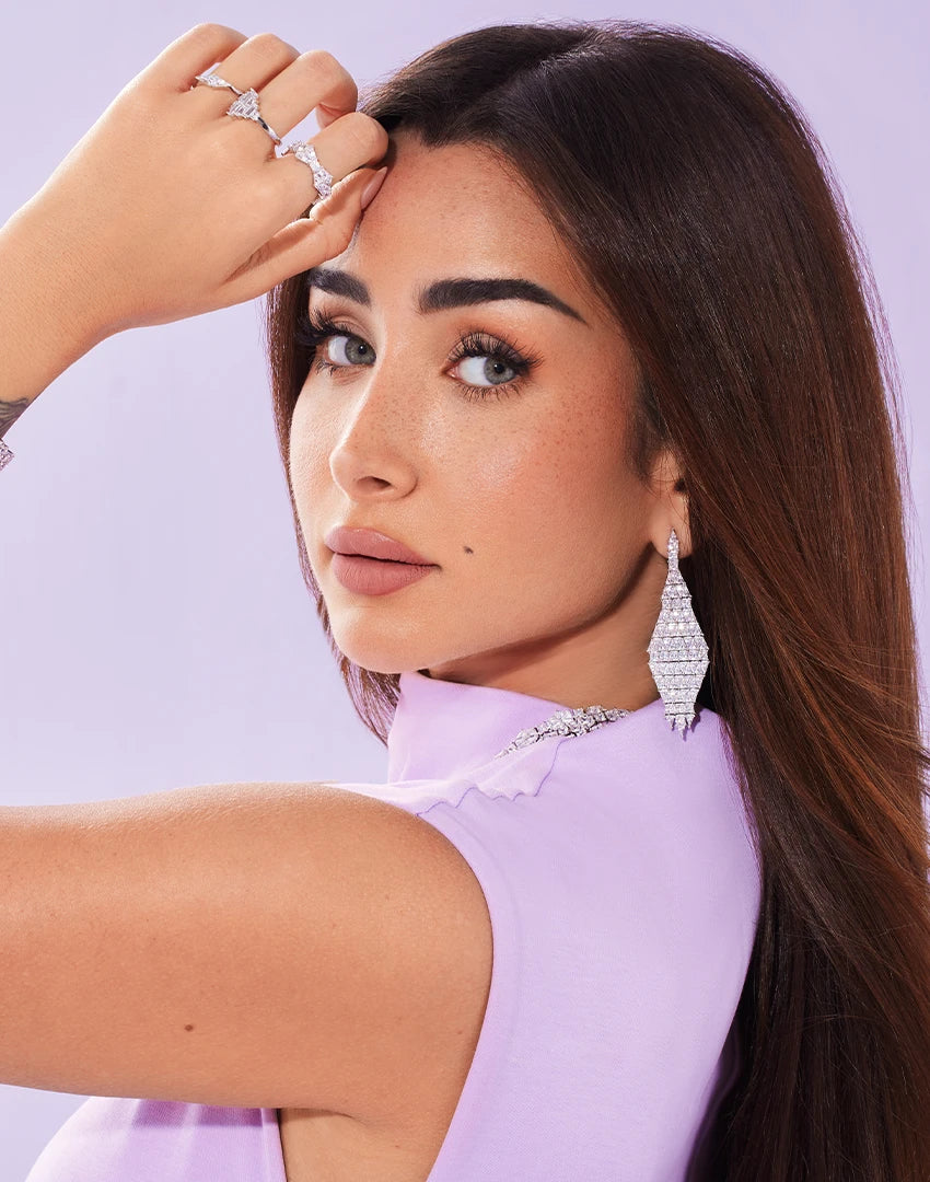 Hannah in a light purple outfit with APM MONACO Geometric jewelry set in silver with white stones against a light purple background