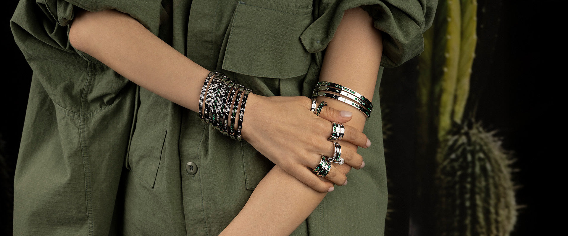 Person wearing multiple morse code bracelets and rings from APM MONACO on a dark background