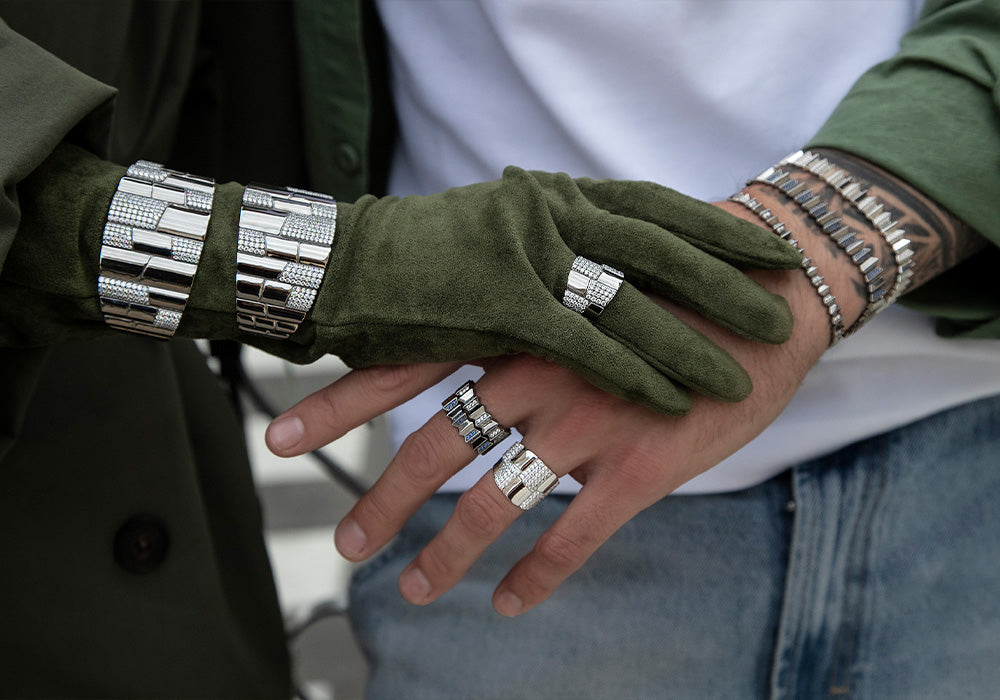 Close-up of hands wearing green gloves and APM MONACO silver bangles with a blurred background
