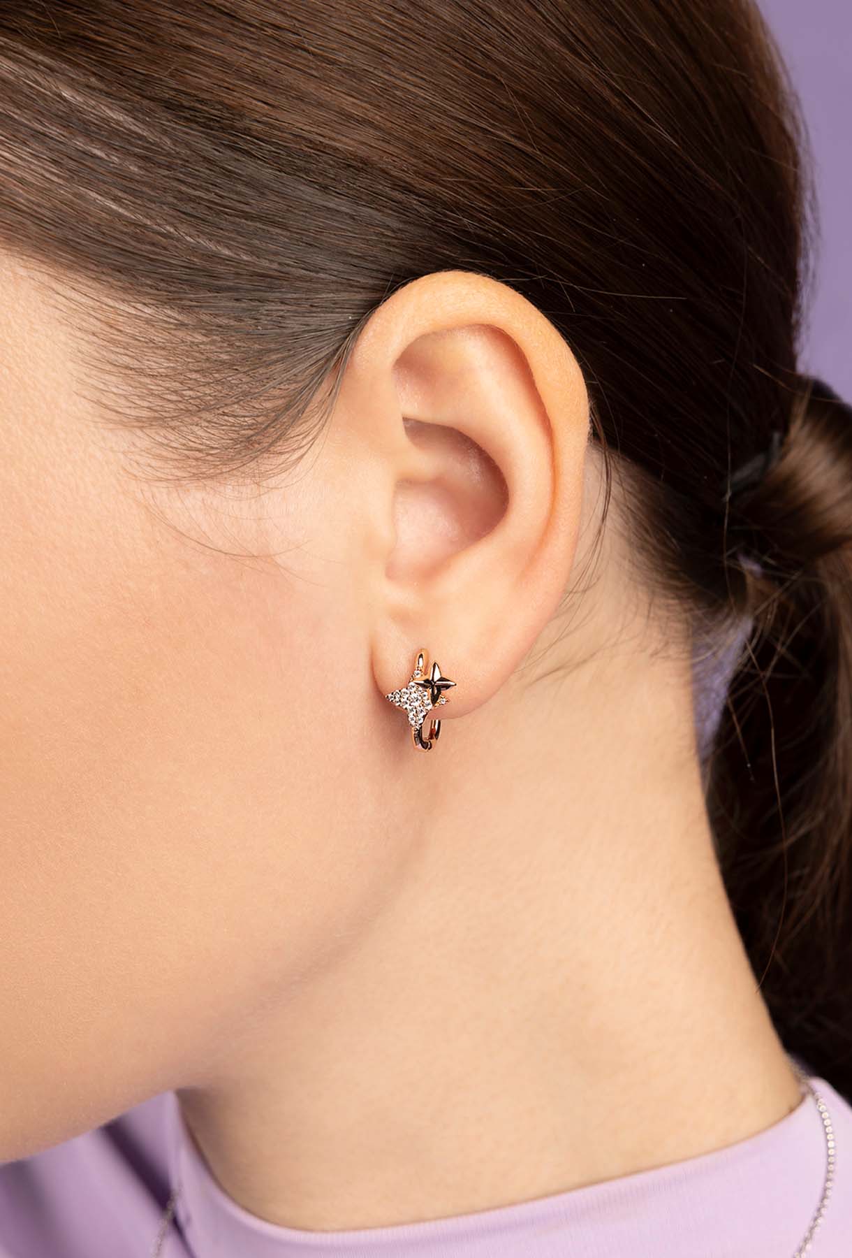 Close-up of an ear wearing a zirconia earring with a blurred background