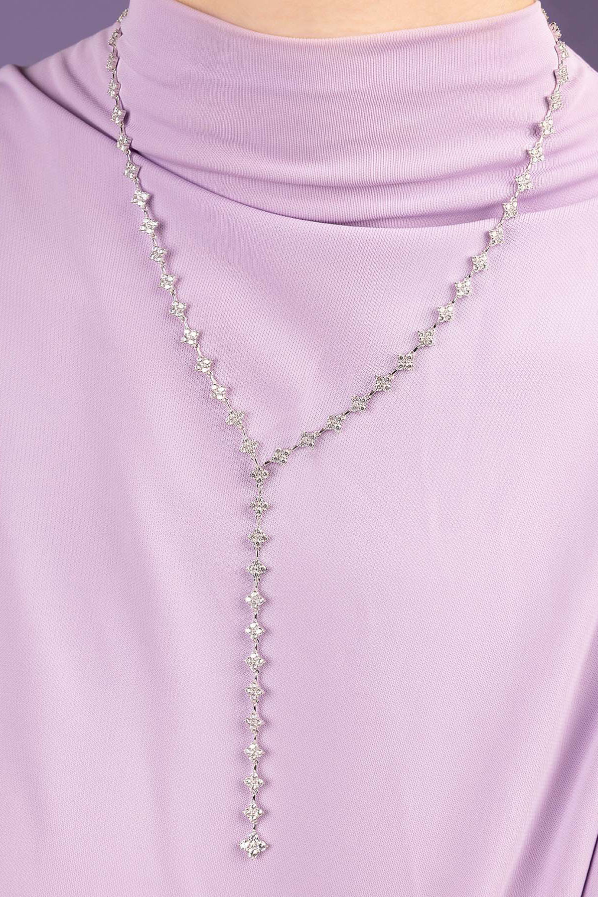 APM MONACO long necklace with clear stones on a person wearing a light purple turtleneck.