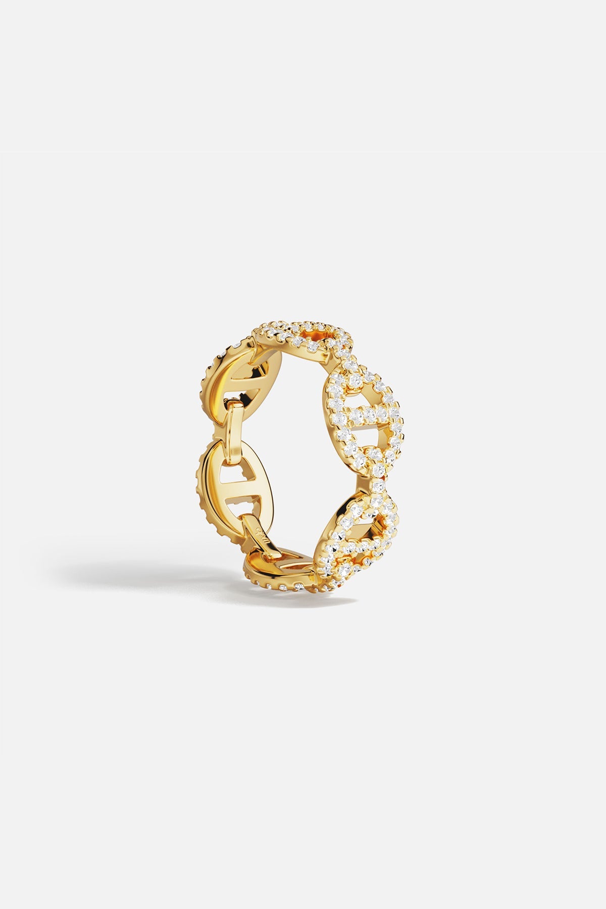 Gold ring with white cubic zirconia accents on a light gray background
