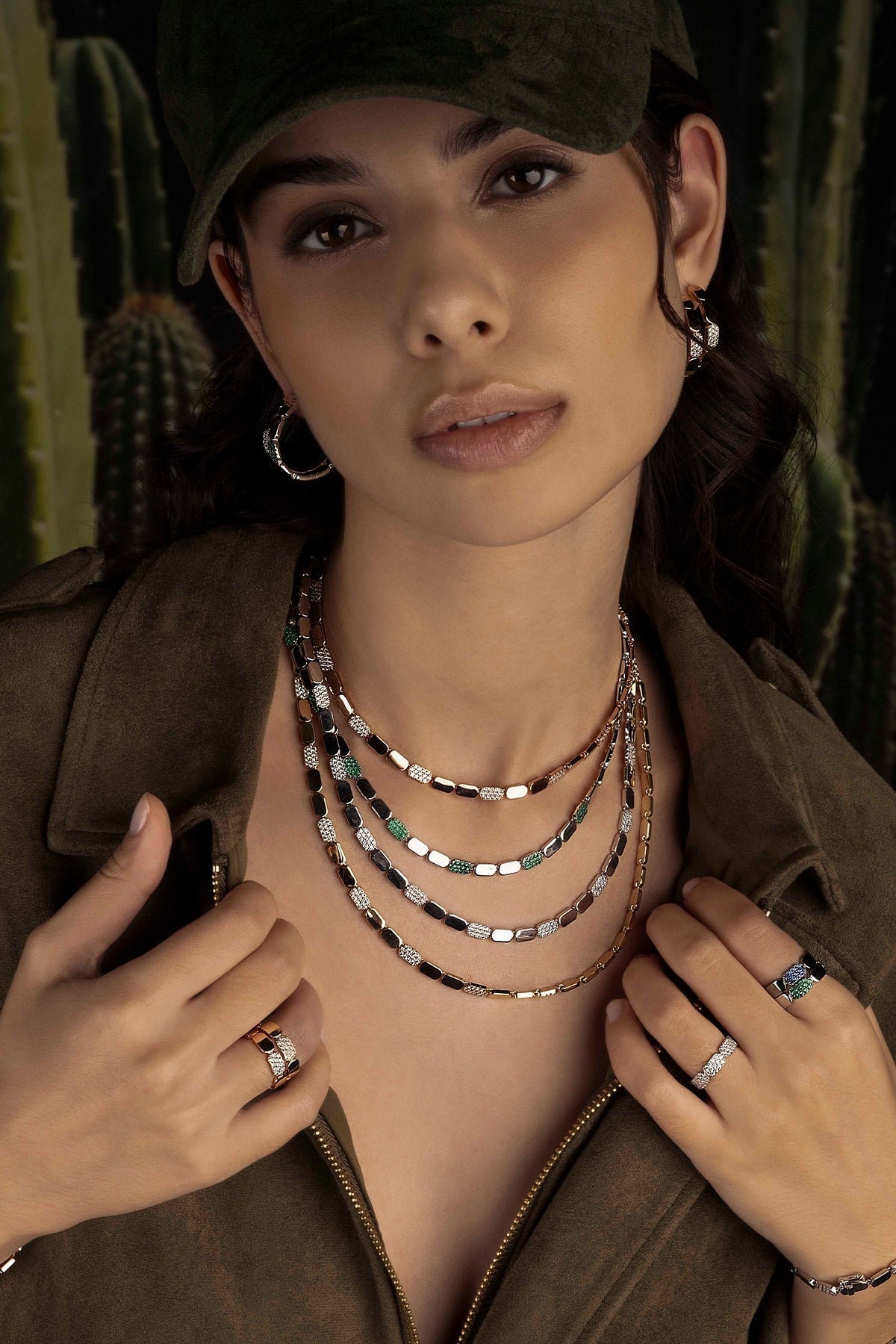 Woman wearing multiple necklaces and rings with a cactus background