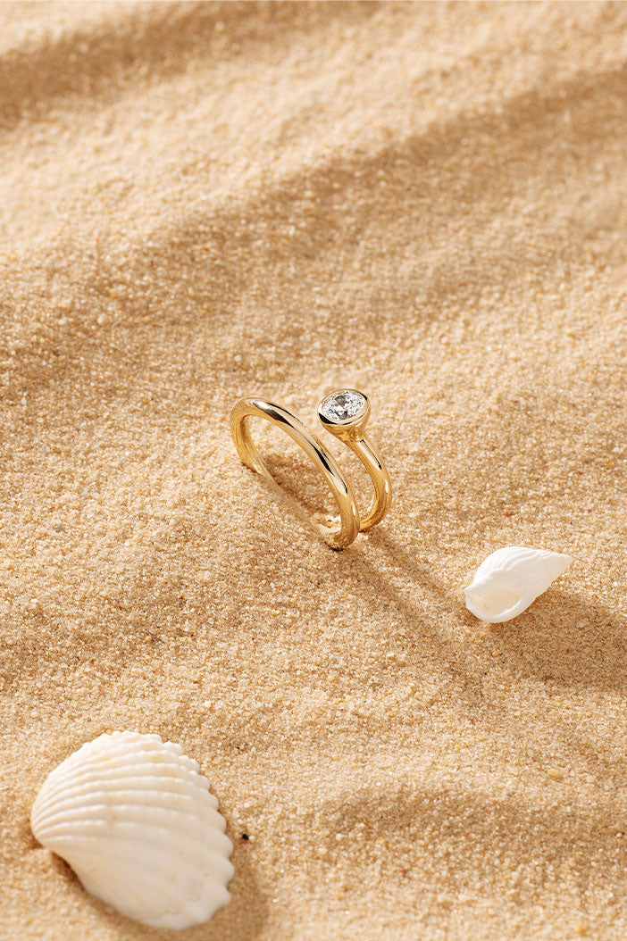 APM Monaco Twist Éclat Ring in Yellow Gold on soft beach
