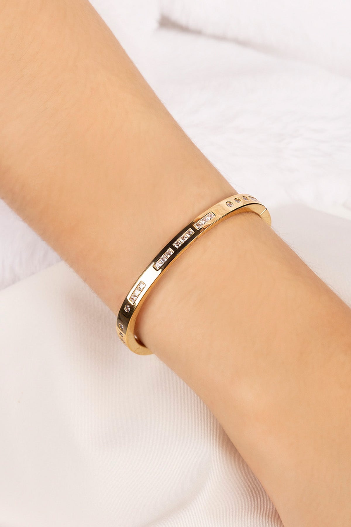 Gold bracelet on a person's wrist against a white background