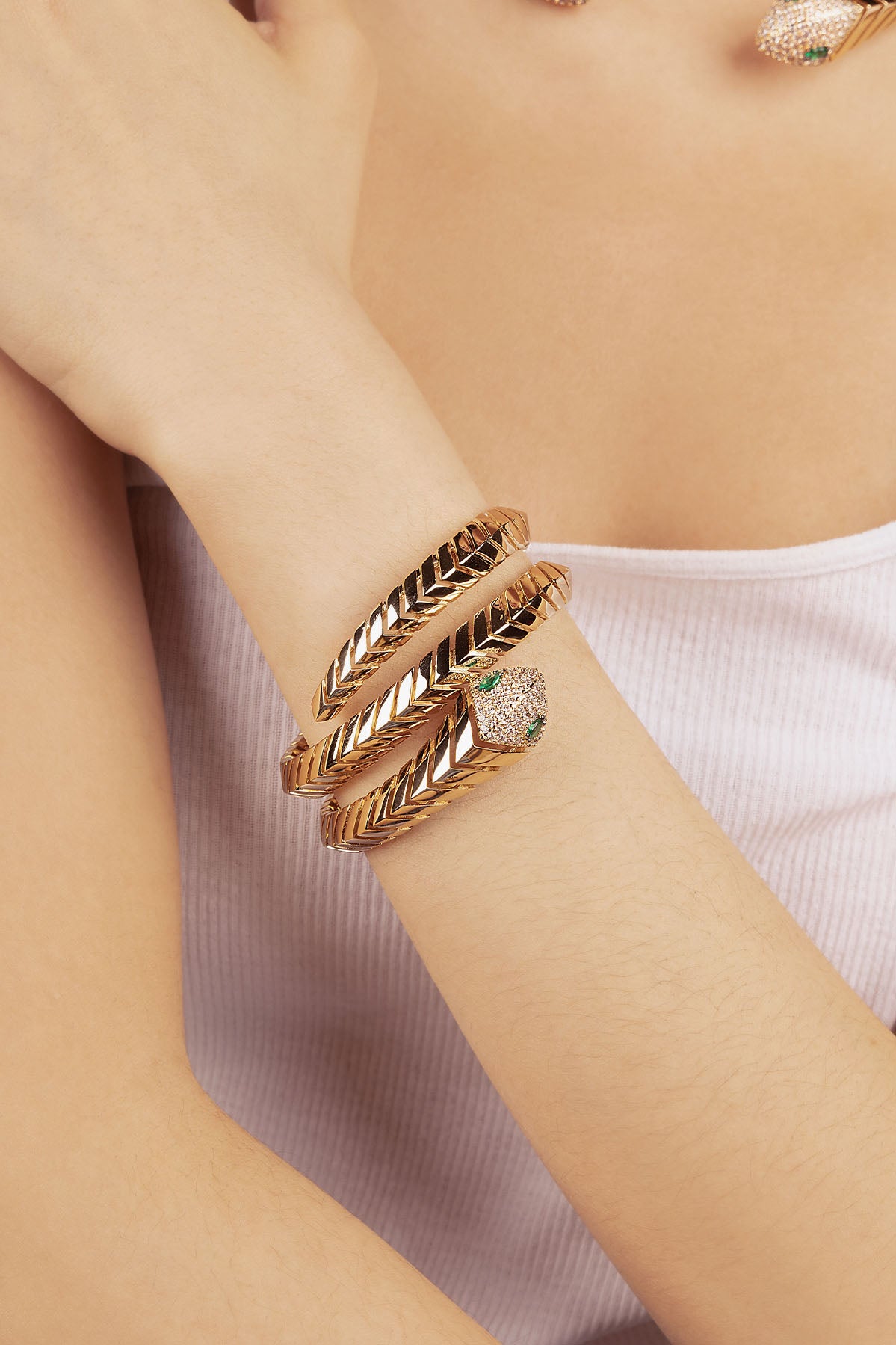 Gold-plated wrap around bangle with white and green zirconia on a woman's wrist