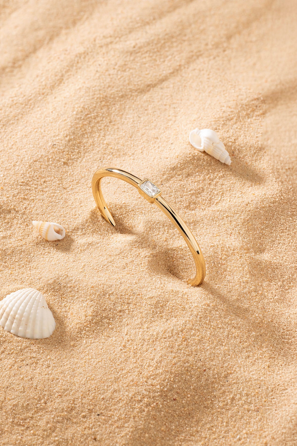 APM Monaco Éclat Cuff in Yellow Gold on soft beach