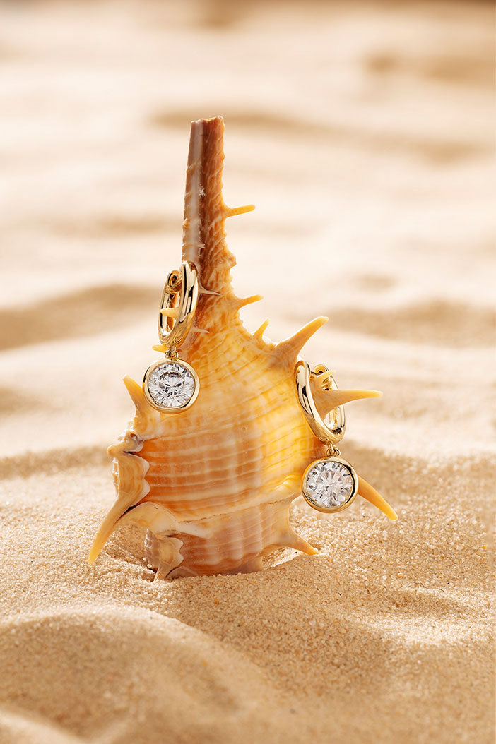 APM Monaco Éclat Hoop Earrings in Yellow Gold on soft beach