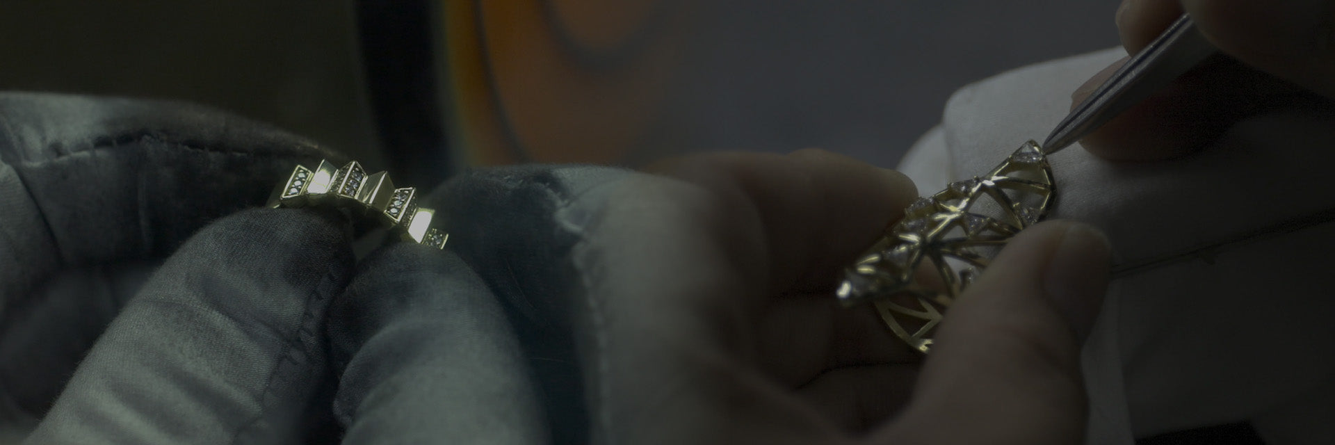 Close-up of hands working on a piece of APM MONACO jewelry with intricate designs.