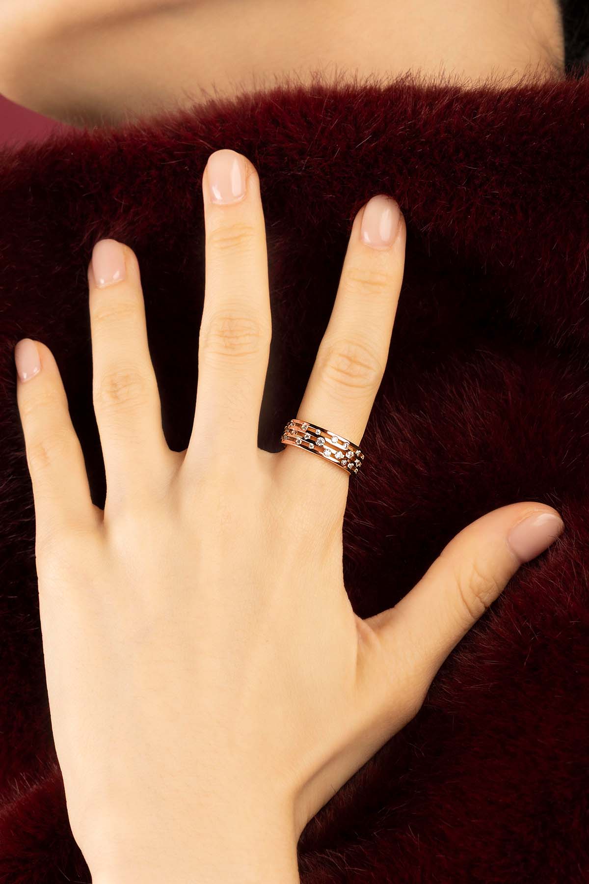 Woman wearing APM ring, delicate rose-hued layers scattered with quiet sparkle.