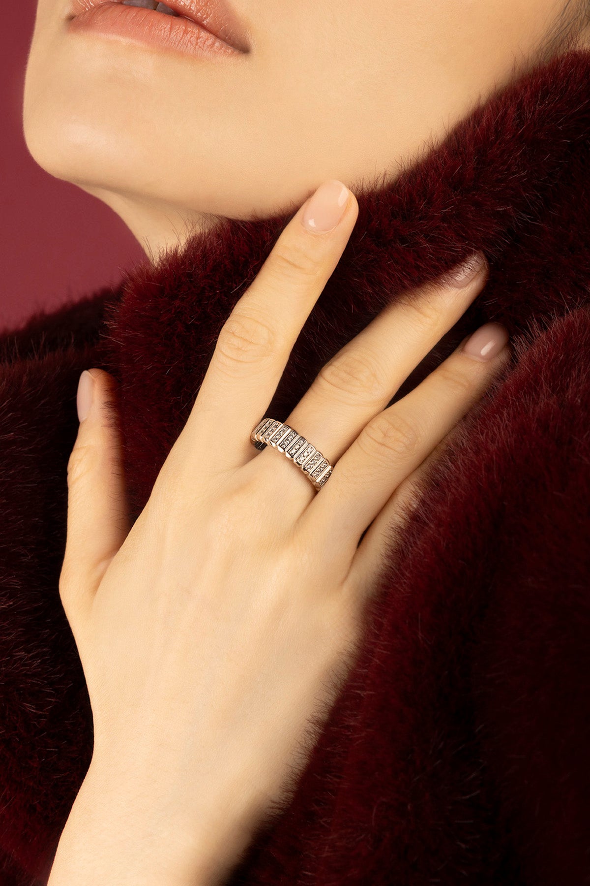 Woman wearing APM Morse Ring, a quiet sparkle against soft burgundy warmth.