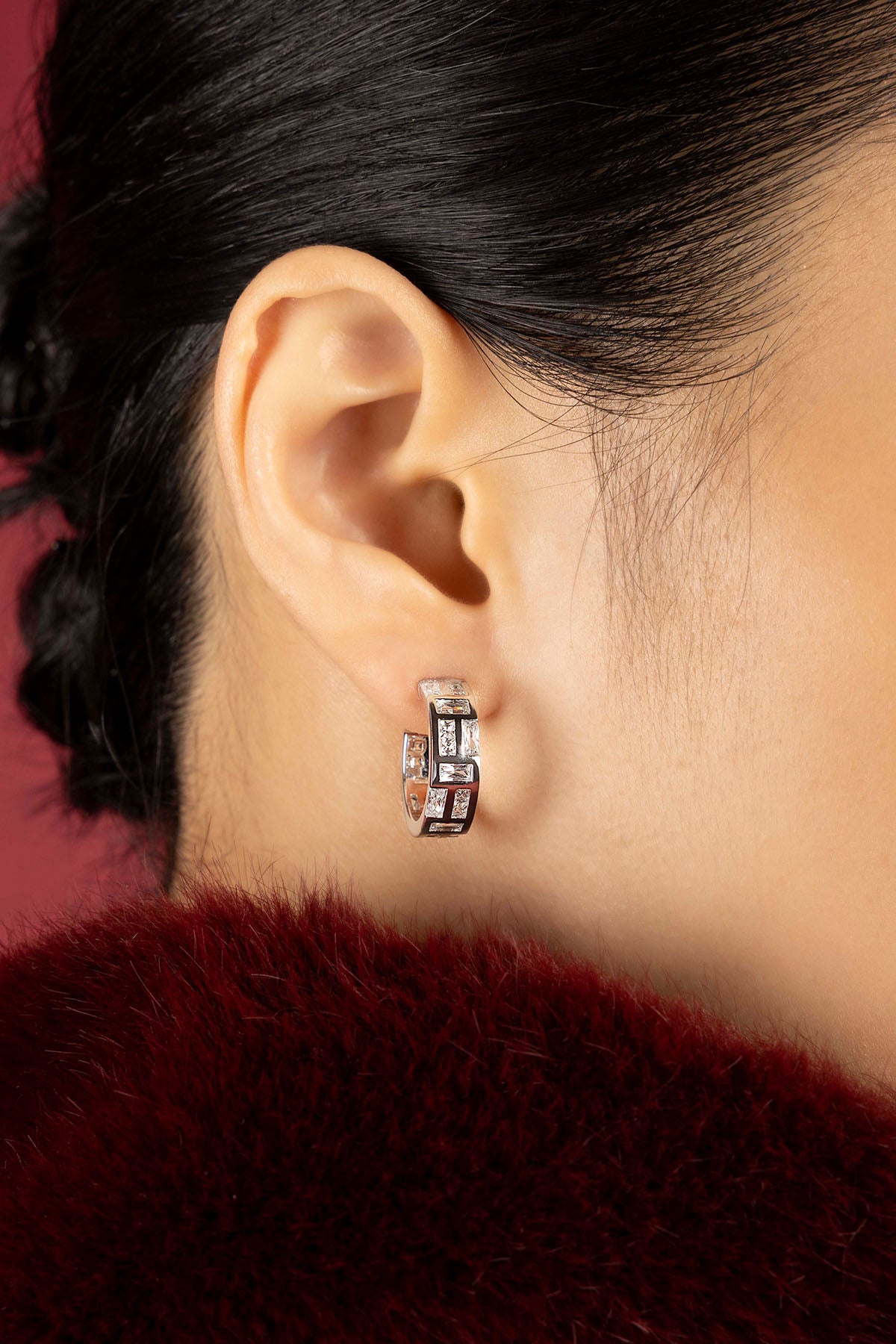 Woman wearing APM hoop earrings, a crystalline sparkle framed in rhodium finish.