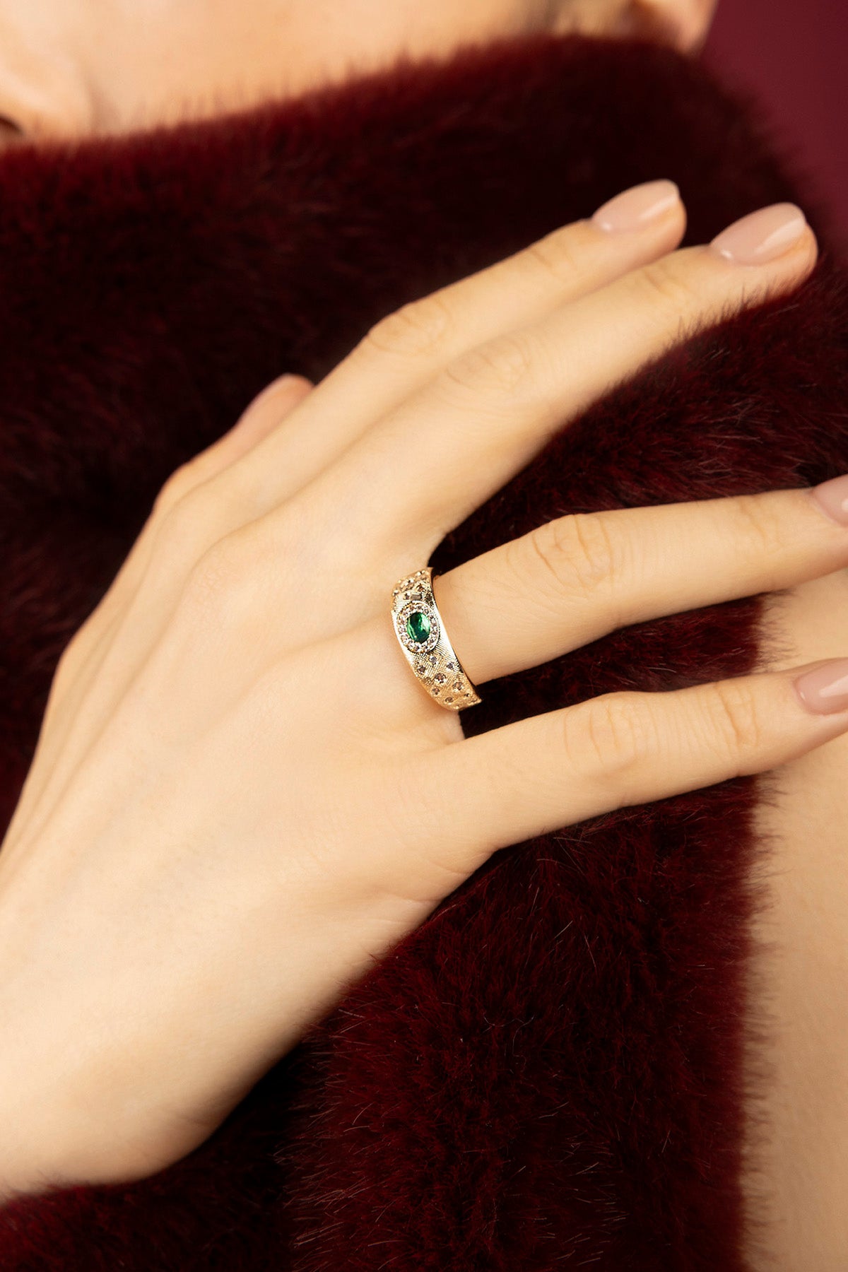 Woman wearing APM ring, a golden whisper of vintage romance and emerald allure.