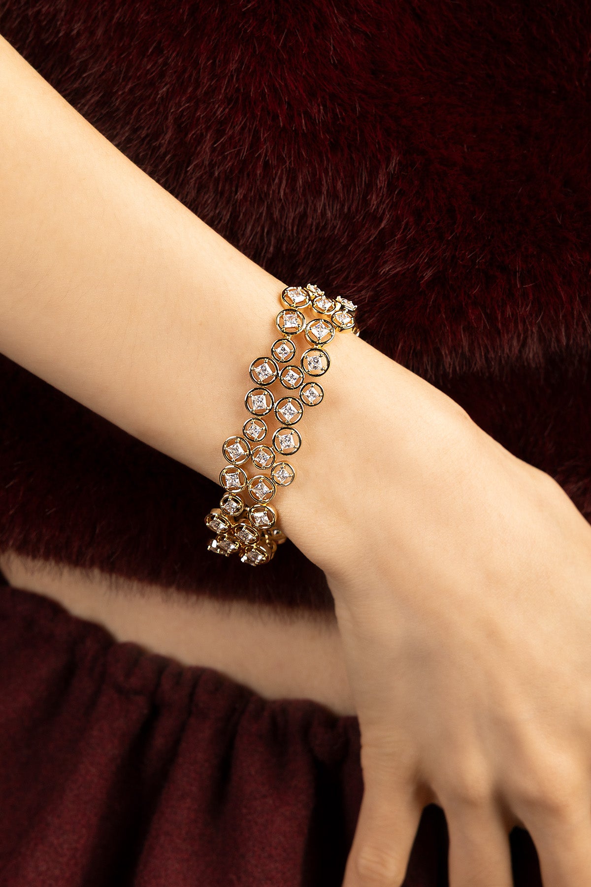 Woman wearing APM Monaco bracelet, a shimmering constellation against velvet warmth.