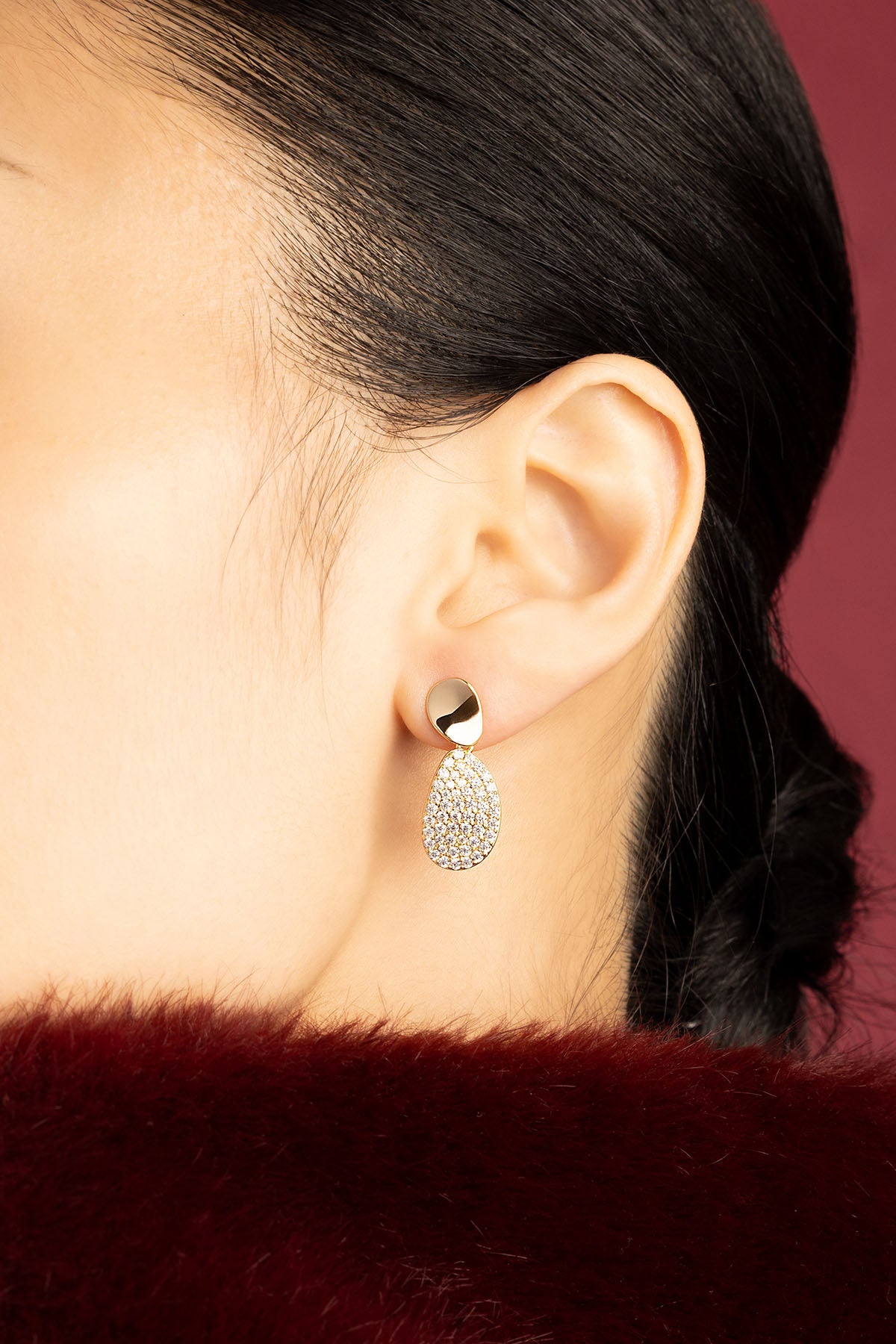 Woman wearing APM Earrings, a golden glow of quiet elegance.