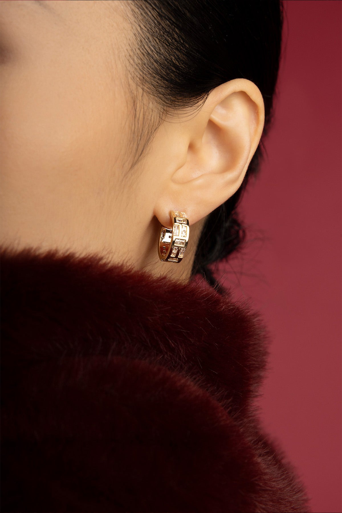 Woman wearing APM Monaco hoop earrings, a golden whisper against winter's warmth.