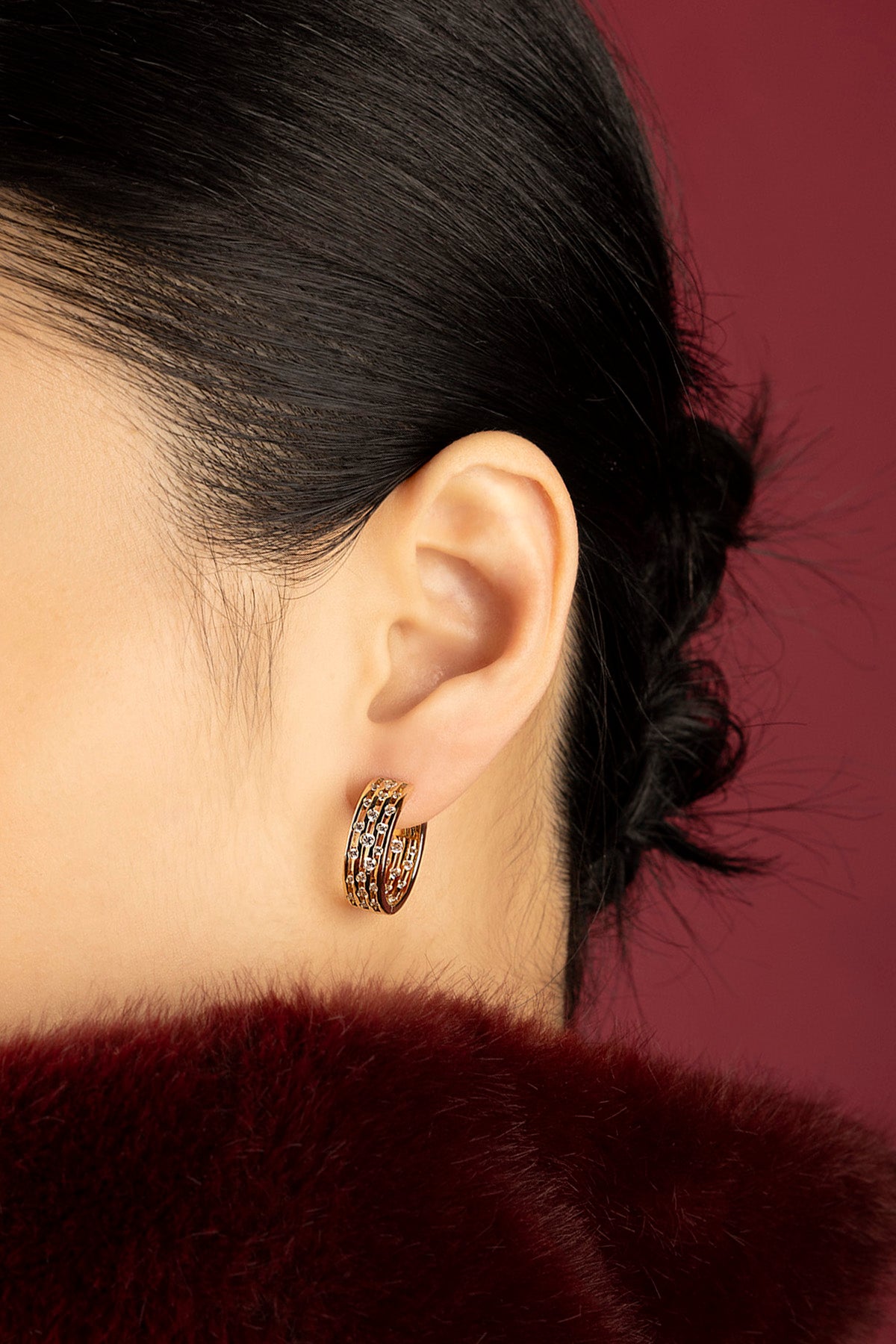 Woman wearing APM Monaco hoop earrings, a golden whisper of quiet allure.