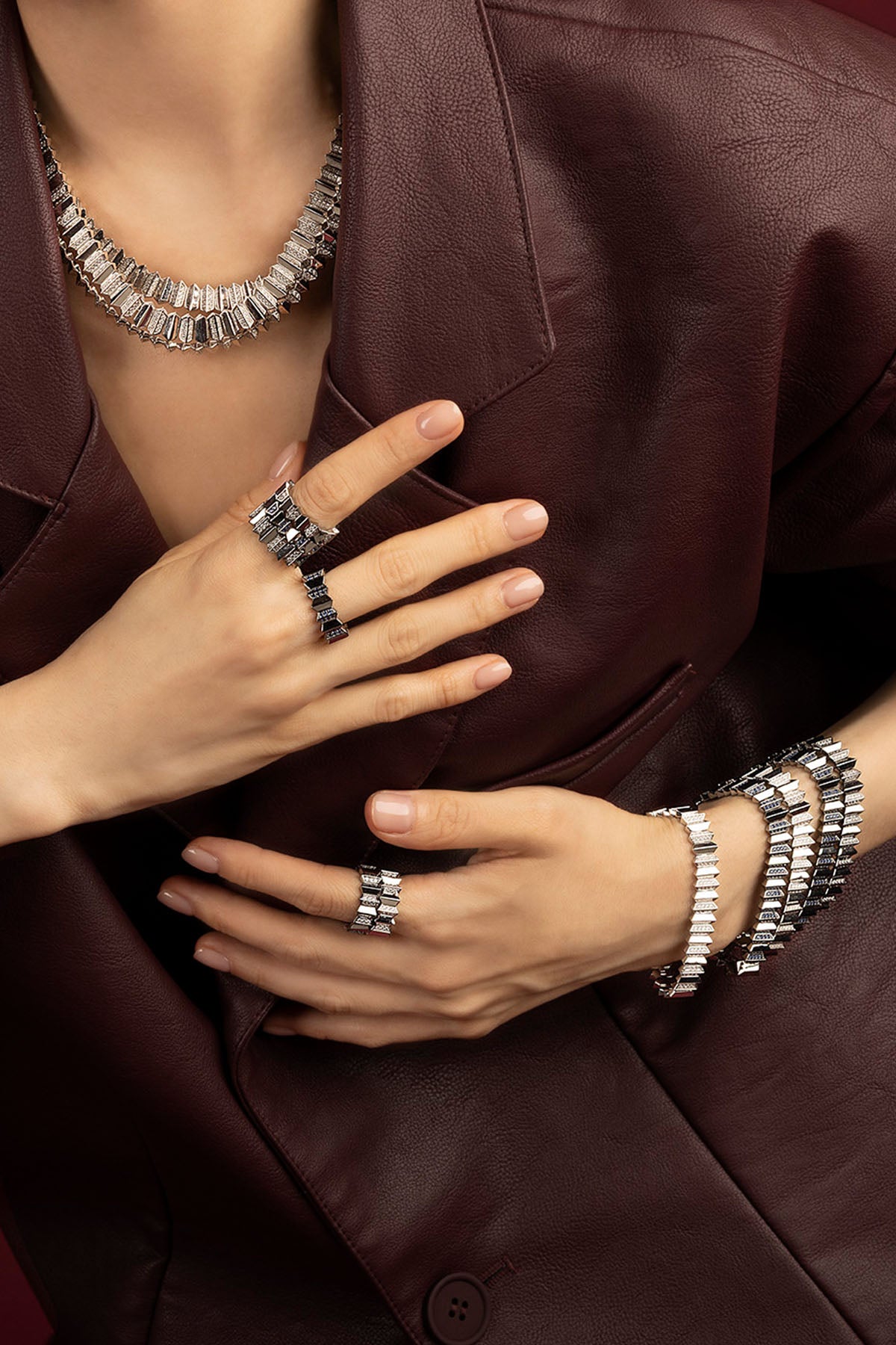 Woman wearing APM Morse jewelry set, bold rhodium finish meets quiet burgundy elegance.