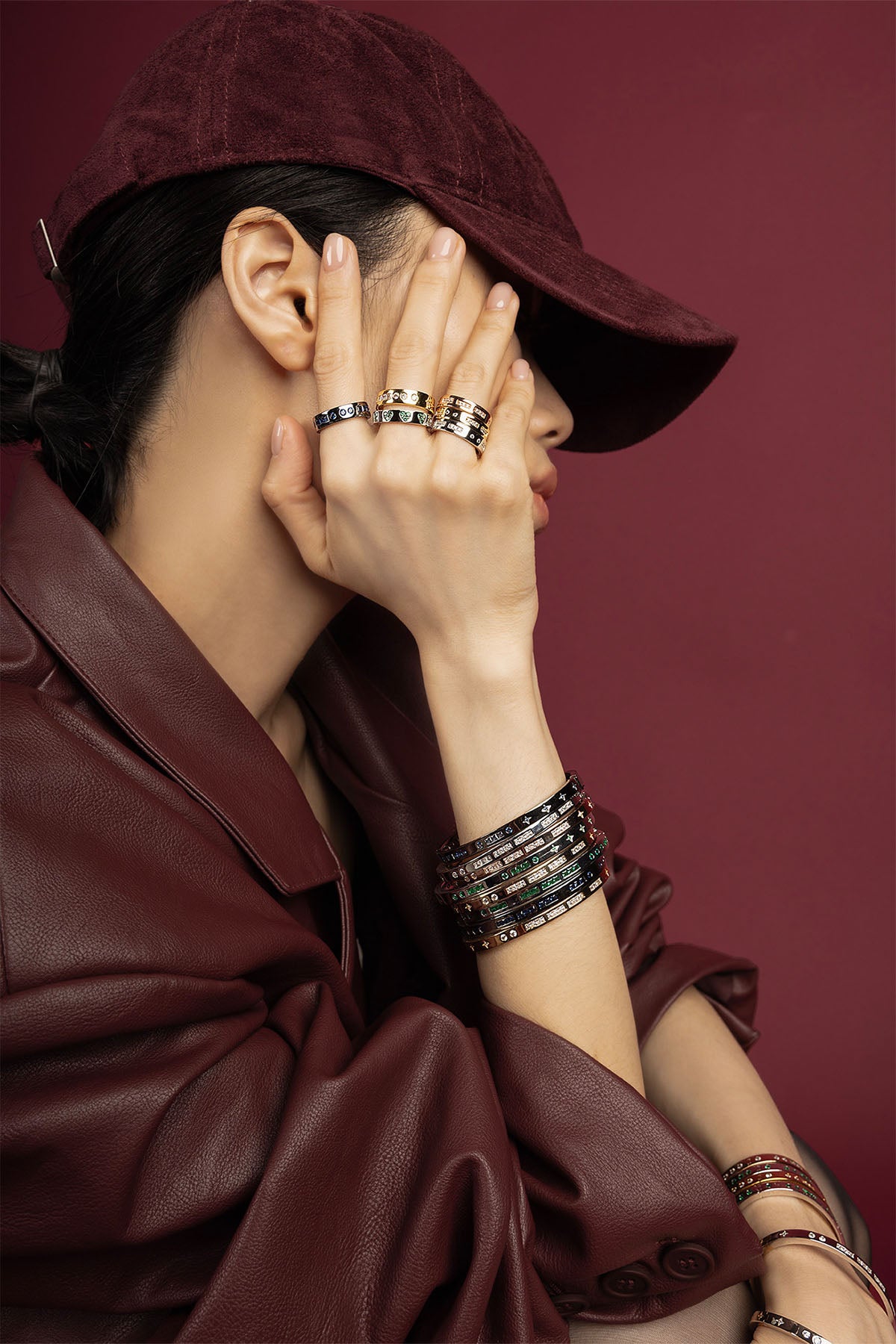 Woman wearing APM stacked rings and bangles, a bold burgundy statement.