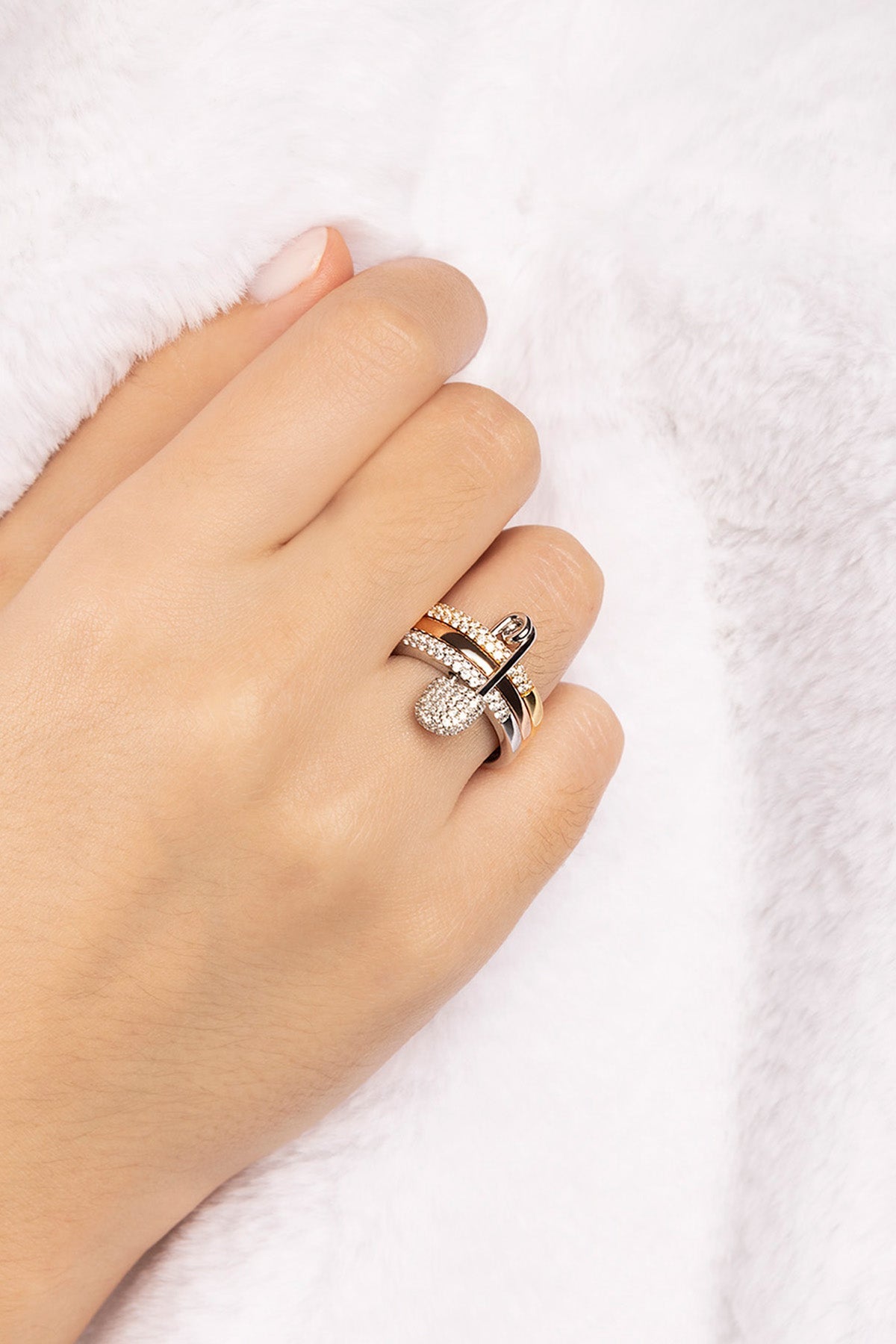 Hand wearing a love smile triple hoop safety pin ring from APM MONACO on a white background