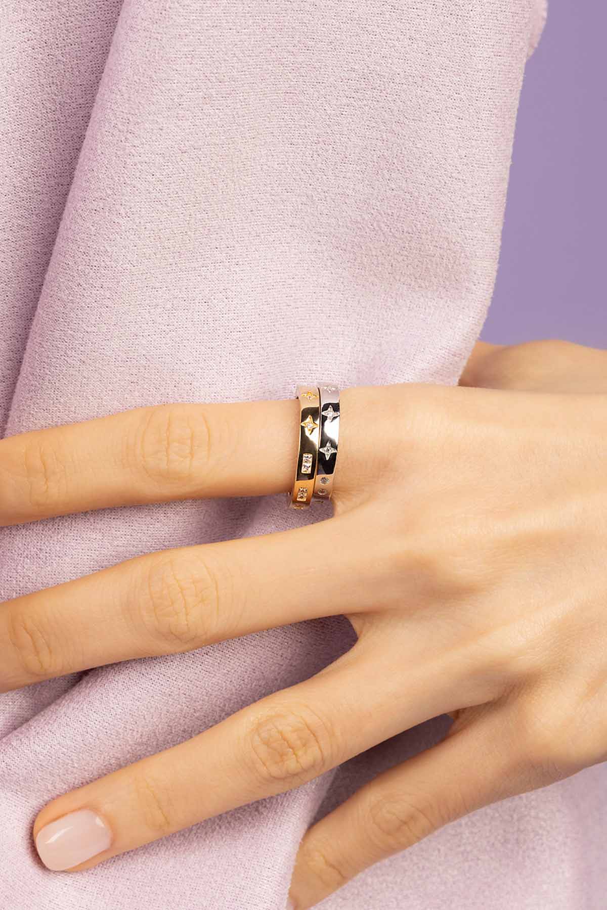 Hand wearing a ring with a purple fabric background