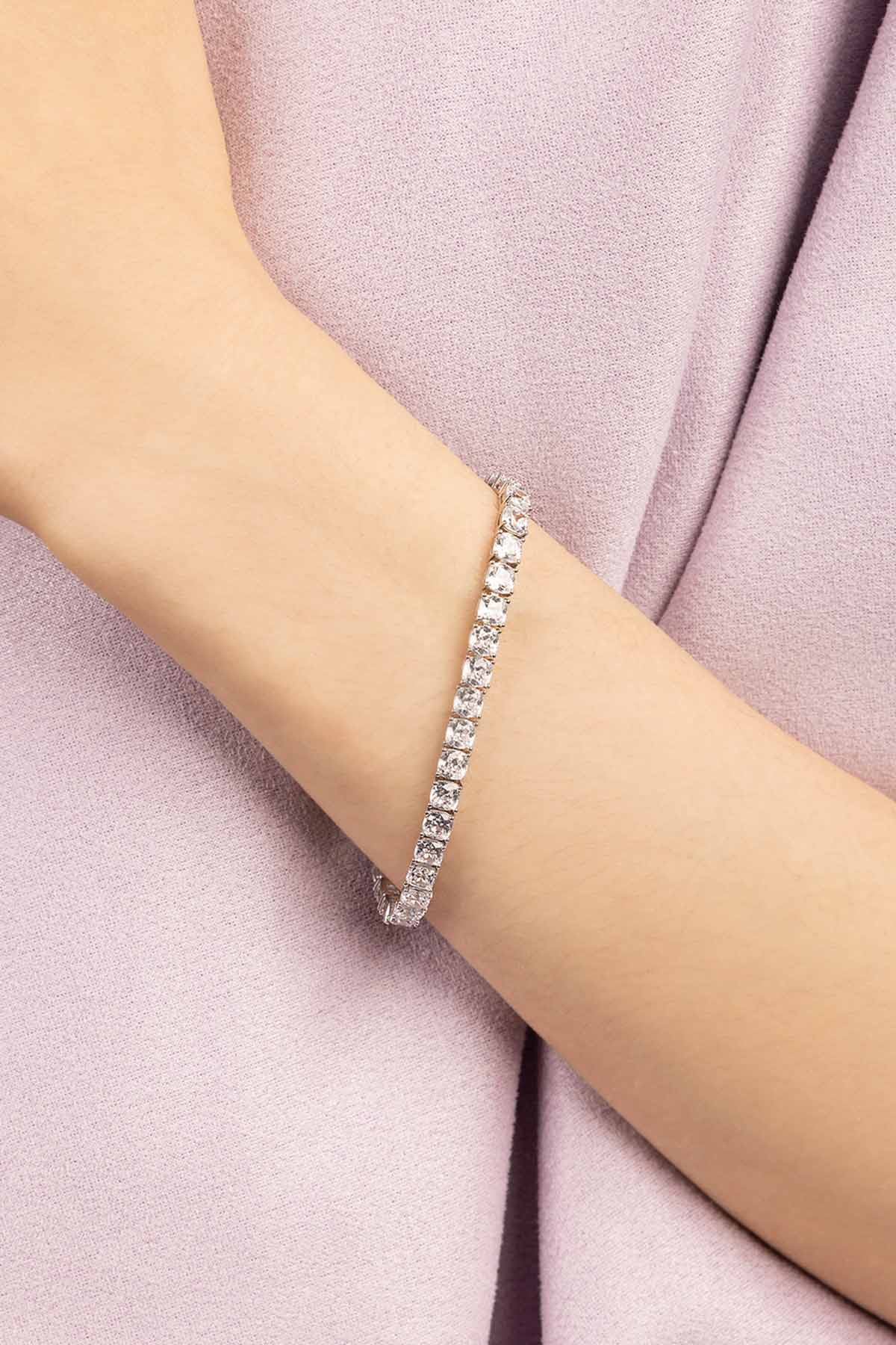Silver bracelet on a person's wrist with a soft pink fabric background
