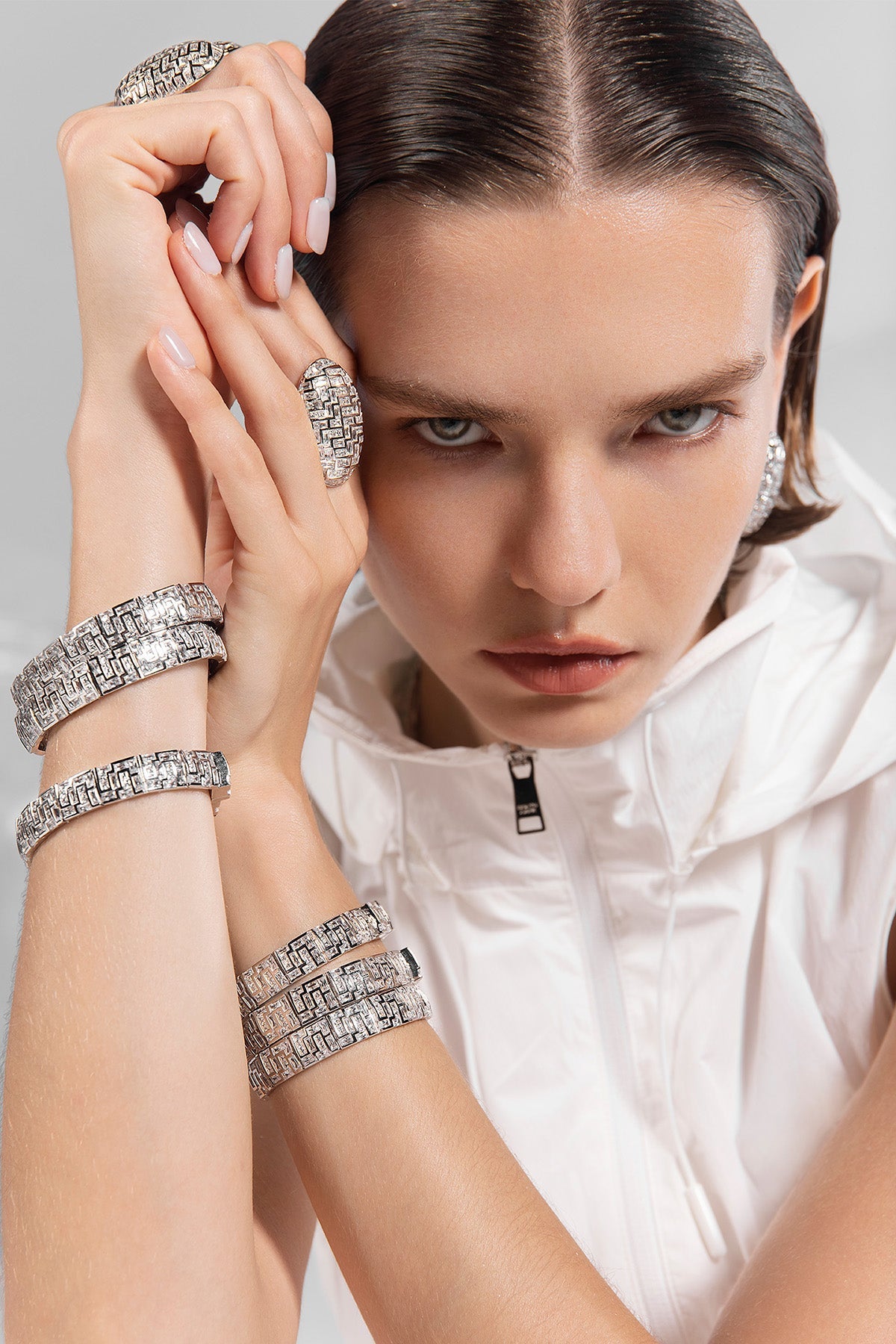 Woman wearing multiple silver chunky bracelets and rings from APM MONACO on a gray background