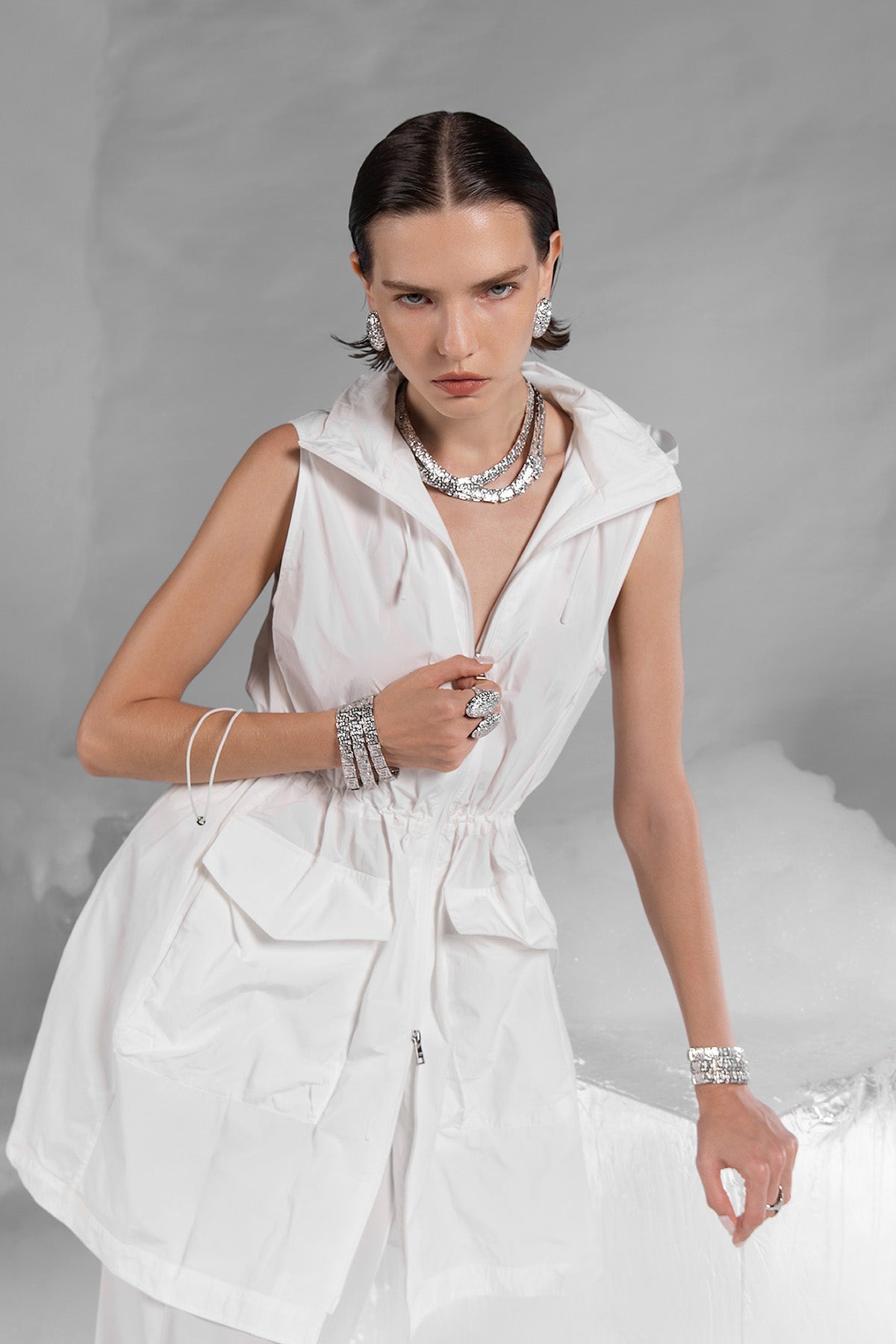 Woman wearing multiple silver chunky bracelets and rings from APM MONACO on a gray background